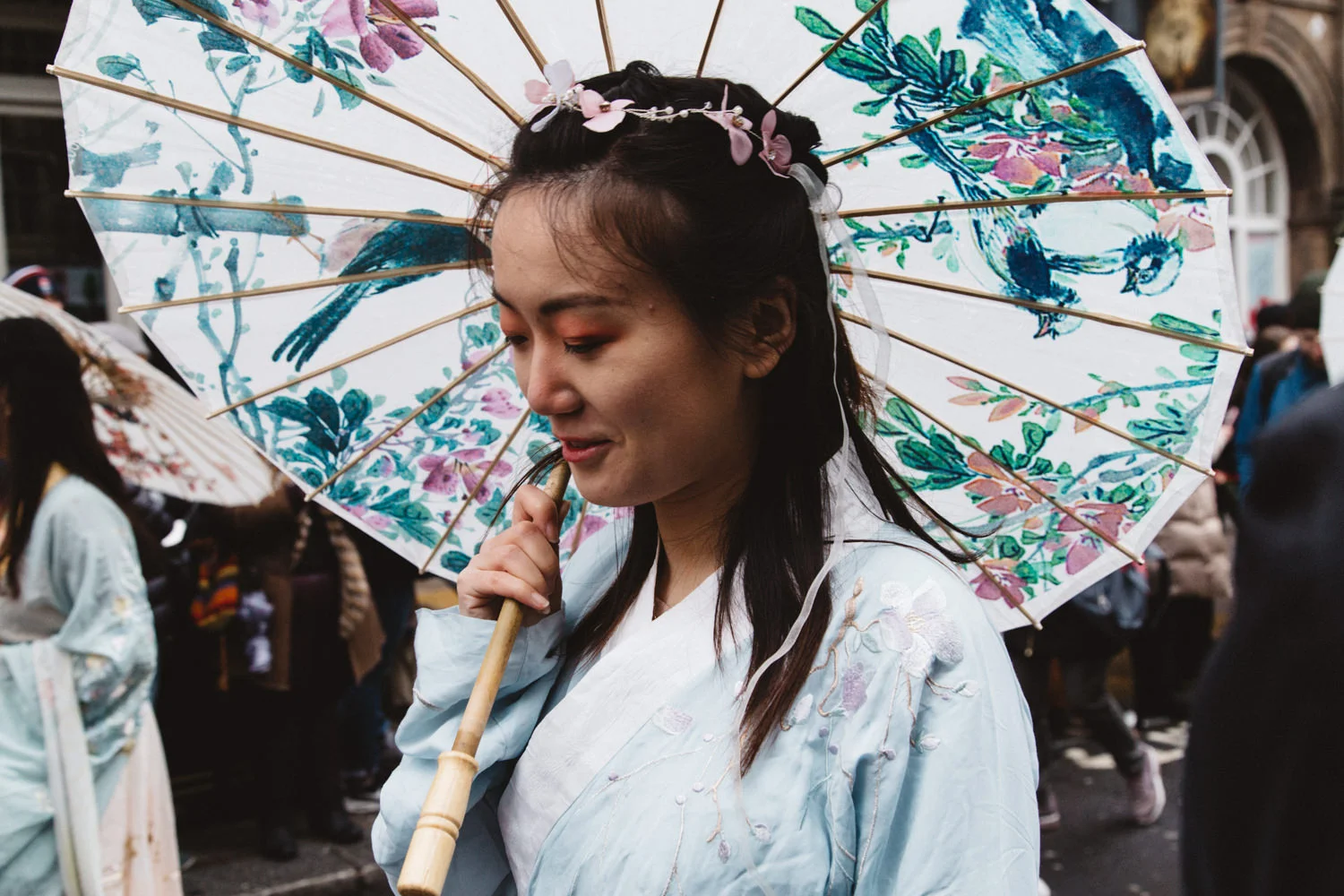 Chinese woman holding an umbrella with flower decorations during the Chinese New Year Parade in London
