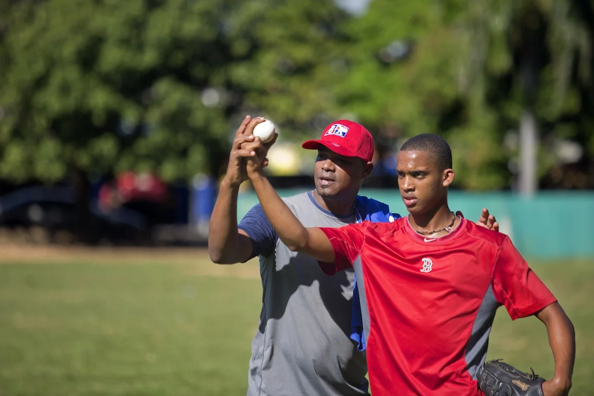 Gipsy Veras works with a teen pitcher on his fastball during a January morning workout at a university field.