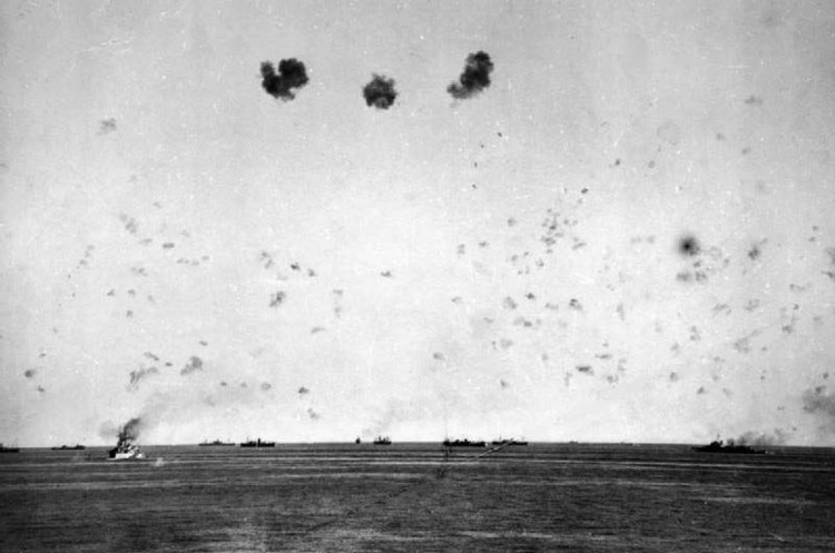 11 August: The loss of HMS EAGLE and the first air attacks: A general view of the convoy under air attack showing the intense anti-aircraft barrage put up by the escorts. The battleship HMS RODNEY is on the left and the cruiser HMS MANCHESTER on the…