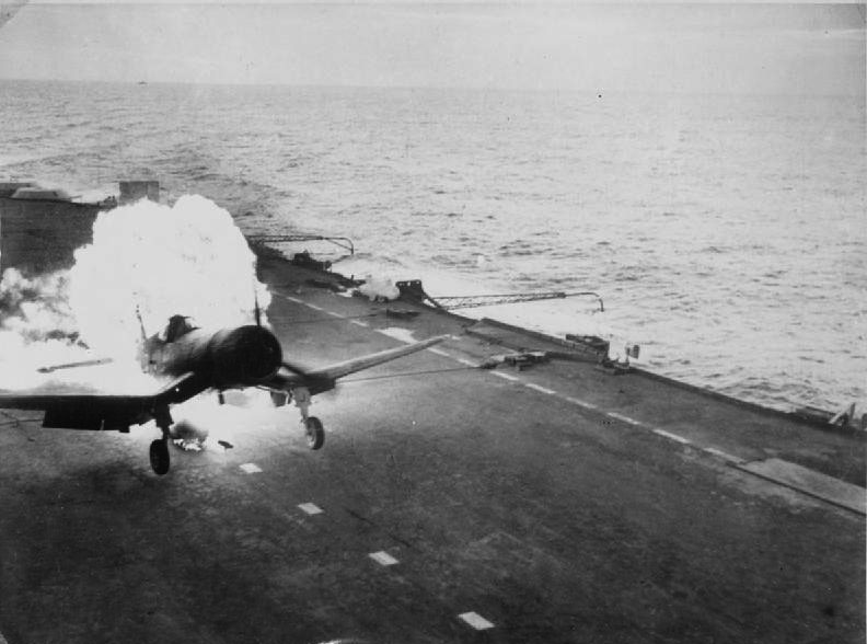 On board a British Pacific fleet carrier operating against the Japanese. Lieutenant Commander (A) Freddy Charlton, British Fleet Air Arm pilot, had a remarkable escape when the long-range petrol tank of his Chance-Vought Corsair fighter burst into flames (seen here) as he landed on the deck of the aircraft carrier. Both pilot and plane escaped damage.