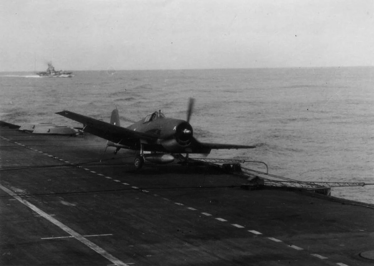 One of HMS INDOMITABLE'S Hellcats swerves towards the deck-edge after grabbing a wire.