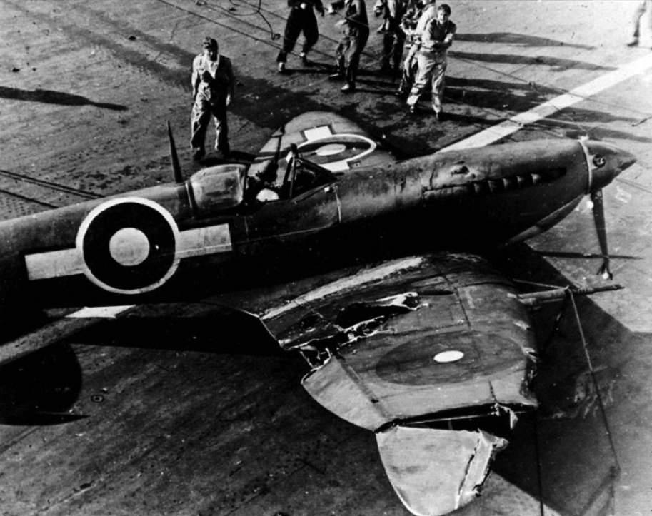 A crashed Seafire aboard HMS INDEFATIGABLE. A large chunk of its wing can be seen to have been carried away by gunfire. The presence of the SEAC roundel on the right wing simply represents the use of a spare wing component not painted for the Pacific theatre.