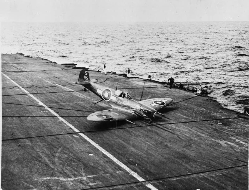 A successful "belly landing" by a British Pacific Fleet Supermarine Seafire, whose undercarriage was damaged during on operation against the Japanese. Photograph possibly taken on board HMS INDEFATIGABLE. Note the arrester wires lying across the deck.