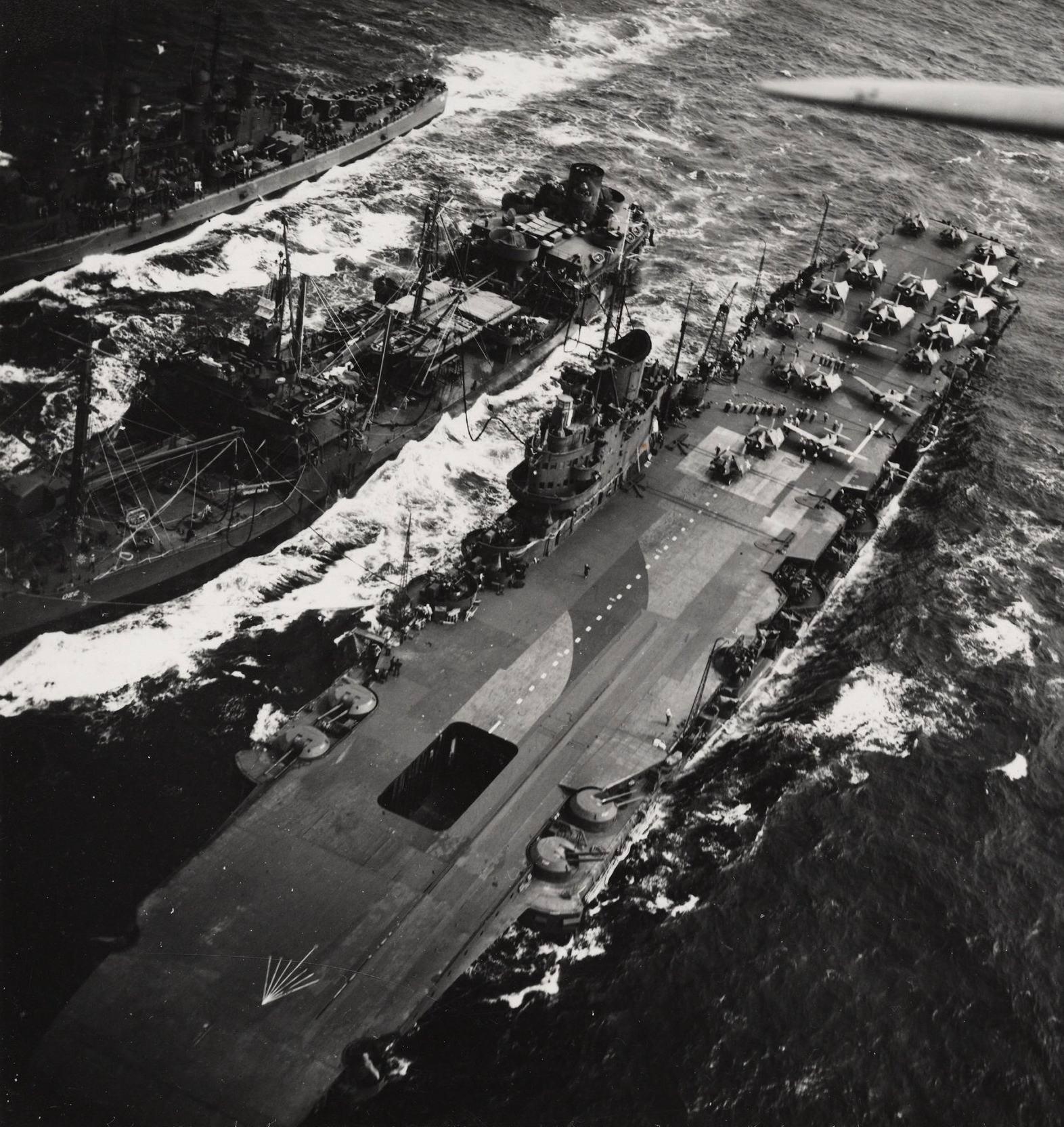 A US anti-aircraft cruiser and HMS VICTORIOUS both take on fuel.
