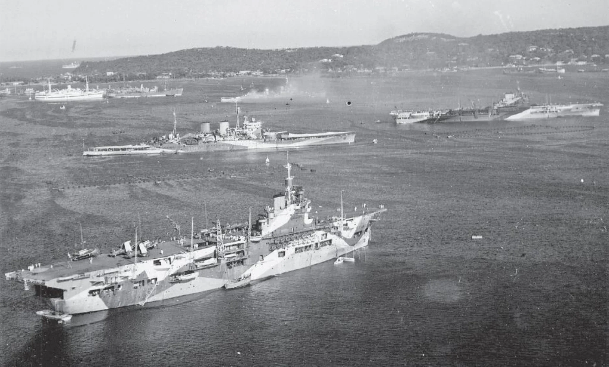 The forward elements of the new core of the British Eastern Fleet, pictured at Trincomalee in February 1944. In the foreground is HMS Unicorn, with the battlecruiser HMS Renown above and HMS Illustrious to the right. The cruiser partially obscured by smoke is either HMS Ceylon or HMNZS Gambia. The fresh arrivals from the Home and Mediterranean fleets have not yet been repainted in Eastern Fleet camouflage.