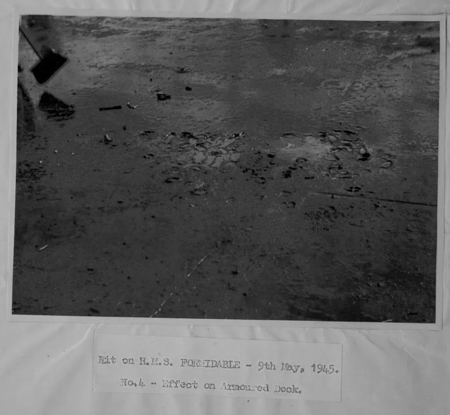 A slight depression and blistered armoured plate was the sum total of damage done to HMS FORMIDABLE by the May 9th kamikaze strike. Top left, a sweeper is manning his broom.