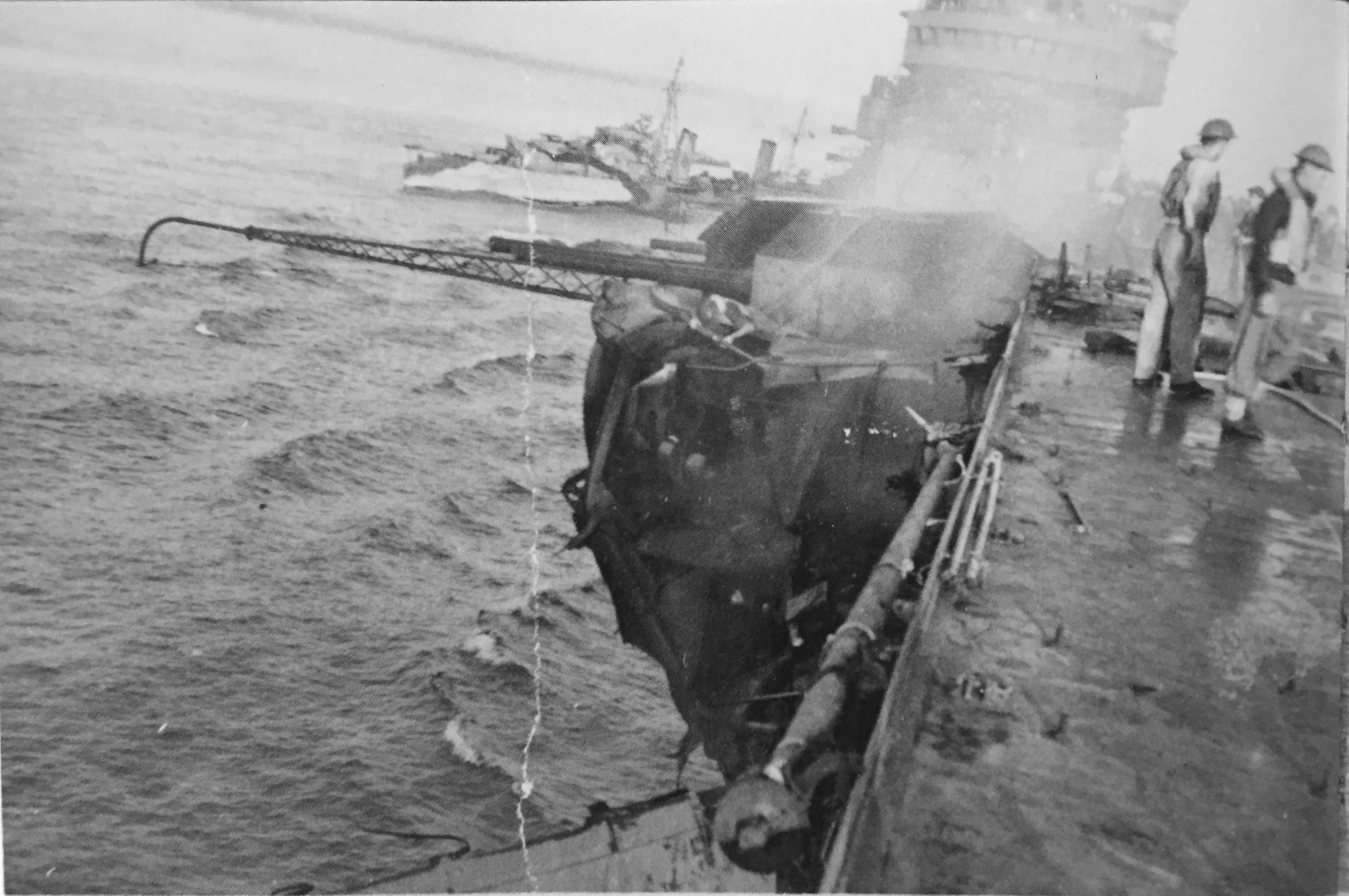 HMS INDOMITABLE's disemboweled A1 turret, shortly after damage control parties doused the flames. HMS CHARYBDIS is crossing the carrier's stern. Picture: FAA Museum