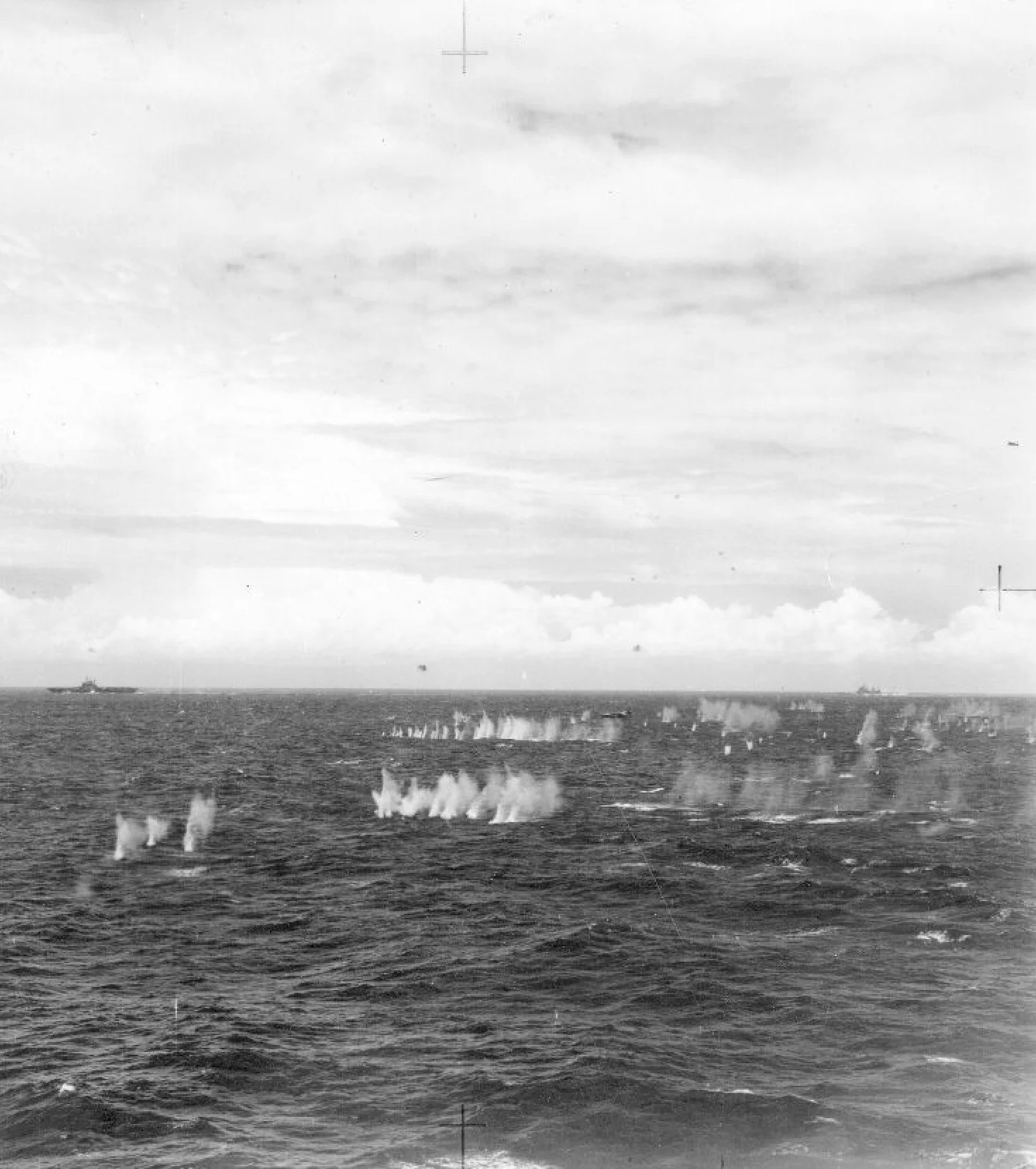 A Ki-21 'Sally' bomber is surrounded by spray kicked up by the close-range anti-aircraft armaments of British Pacific Fleet carriers and escorts. A Seafire can be seen climbing out of the close-defence zone on the right-edge of the picture. This Sally, and up to six others, were shot down. This picture is taken from HMS INDEFATIGABLE, with an unidentified armoured carrier and the battleship King George V in the background.