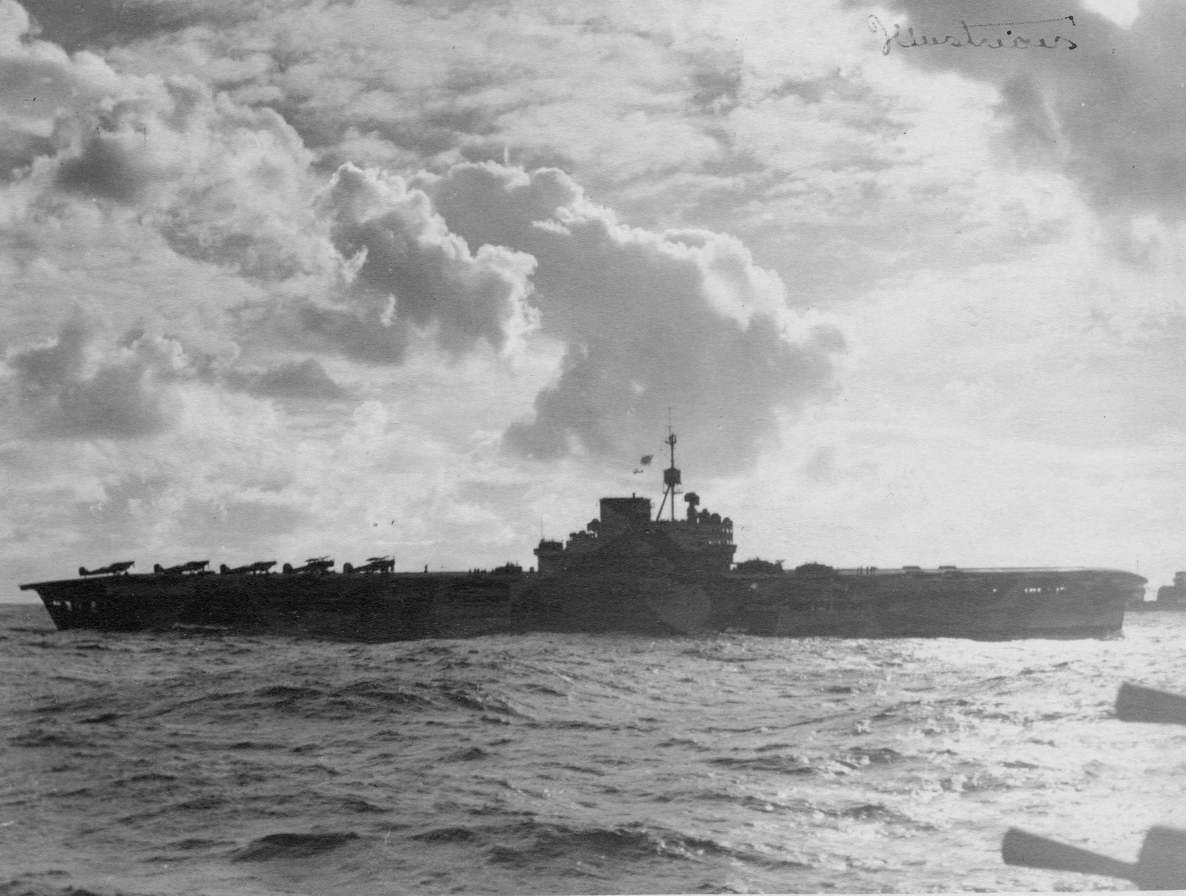 HMS ILLUSTRIOUS with Fulmars and Swordfish spotted ready for take-off on her aft deck.