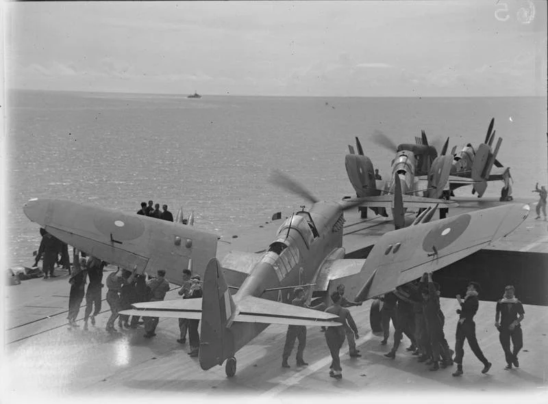 Men folding the wings of a Fairey Firefly of 1770 Squadron, Fleet Air Arm on board HMS INDEFATIGABLE on the aircraft's return from the carrier-borne air strike on the Japanese oil refinery at Pangkalan Brandan, Sumatra. Weather conditions were excellent and the whole weight of bombs and missiles from the Grumman Avengers and Fairey Fireflies fell within the target area. The powerhouse and other important plants, together with oil tanks and buildings, received direct hits.