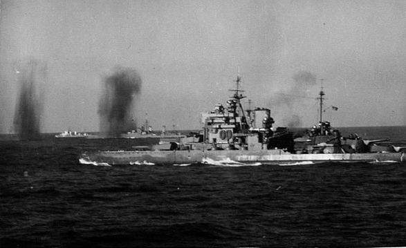 Bombs fall between HMS VALIANT and an escorting cruiser and destroyer.