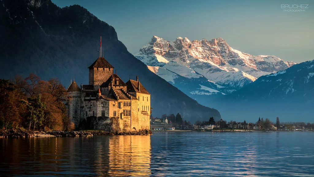 Château de Chillon is an island castle located on Lake Geneva (Lac Léman), south of Veytaux in the canton of Vaud . It is situated at the eastern end of the lake, on the narrow shore between Montreux and Villeneuve , which gives access to the Alpine valley of the Rhone . Chillon is amongst the most visited castles in Switzerland and Europe.