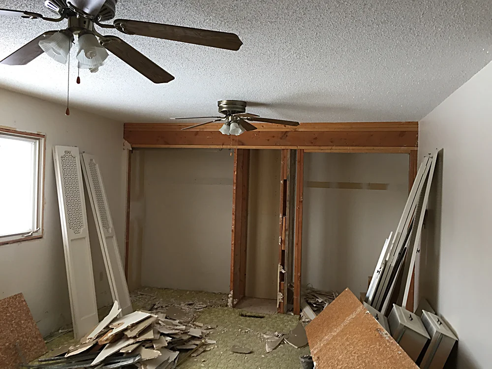 We had not one, but TWO ugly, dusty, rattly ceiling fans in this room! This pictures shows the closets coming down.