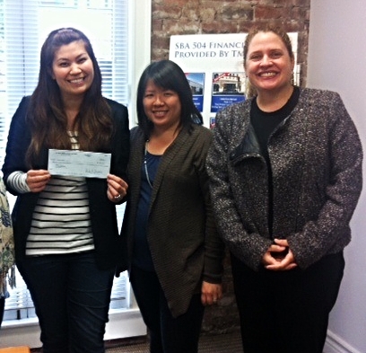 Kelly receives her loan check from Working Solutions Lending Director Agnes & CEO Emily