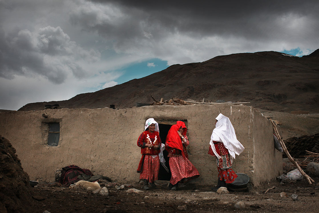 In the villages of Wakhan Corridor, families perform unchanging rituals. The women with their heads covered in white are married, the ones in red aren’t / Dans les villages du corridor du Wakhan, les familles s'organisent autour de rites immuables. Les femmes couvertes de voiles blancs sont mariées, celles en rouge ne le sont pas | AFGHANISTAN