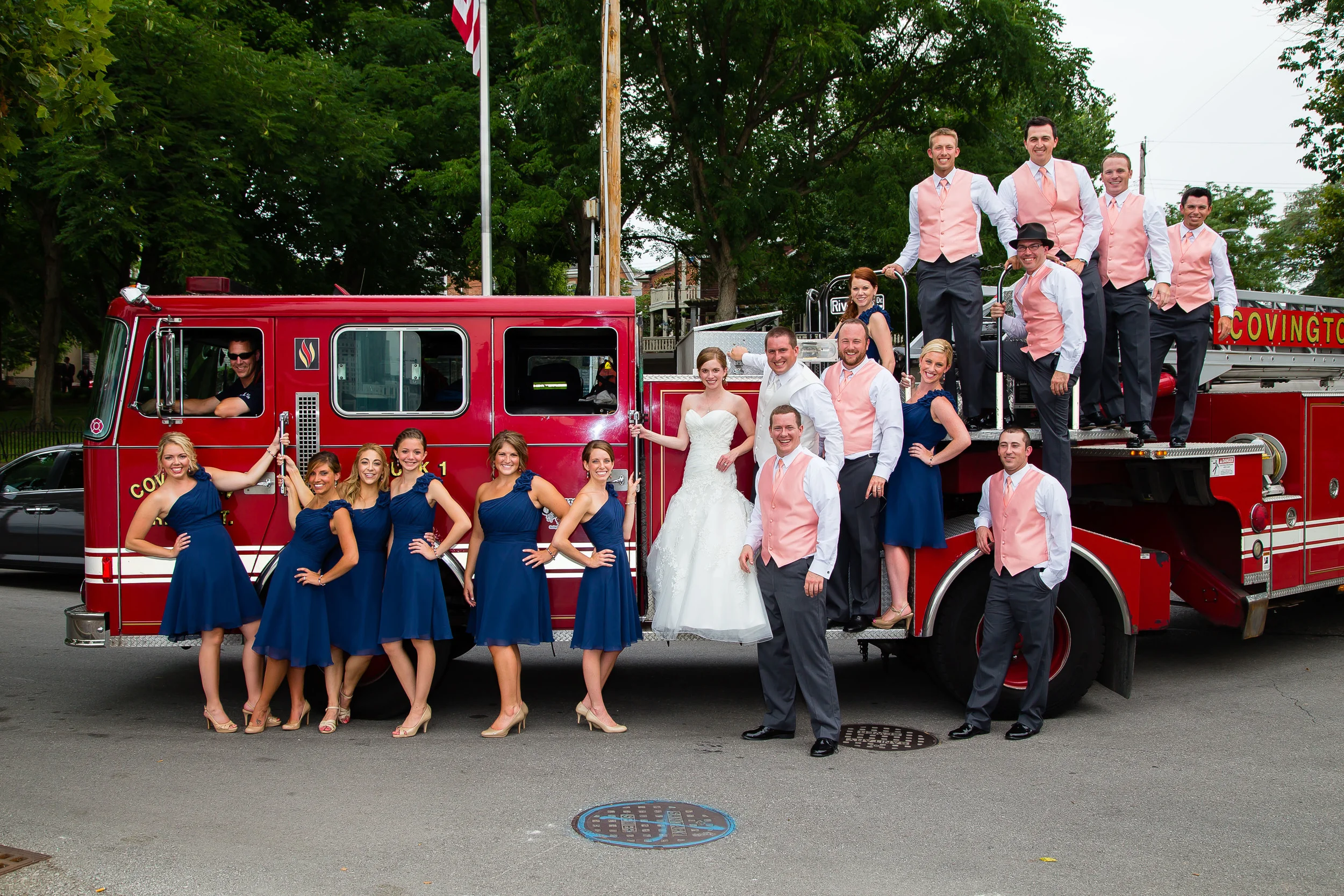 Wedding photograph of a bride and groom with wedding party in front of a fire truck
