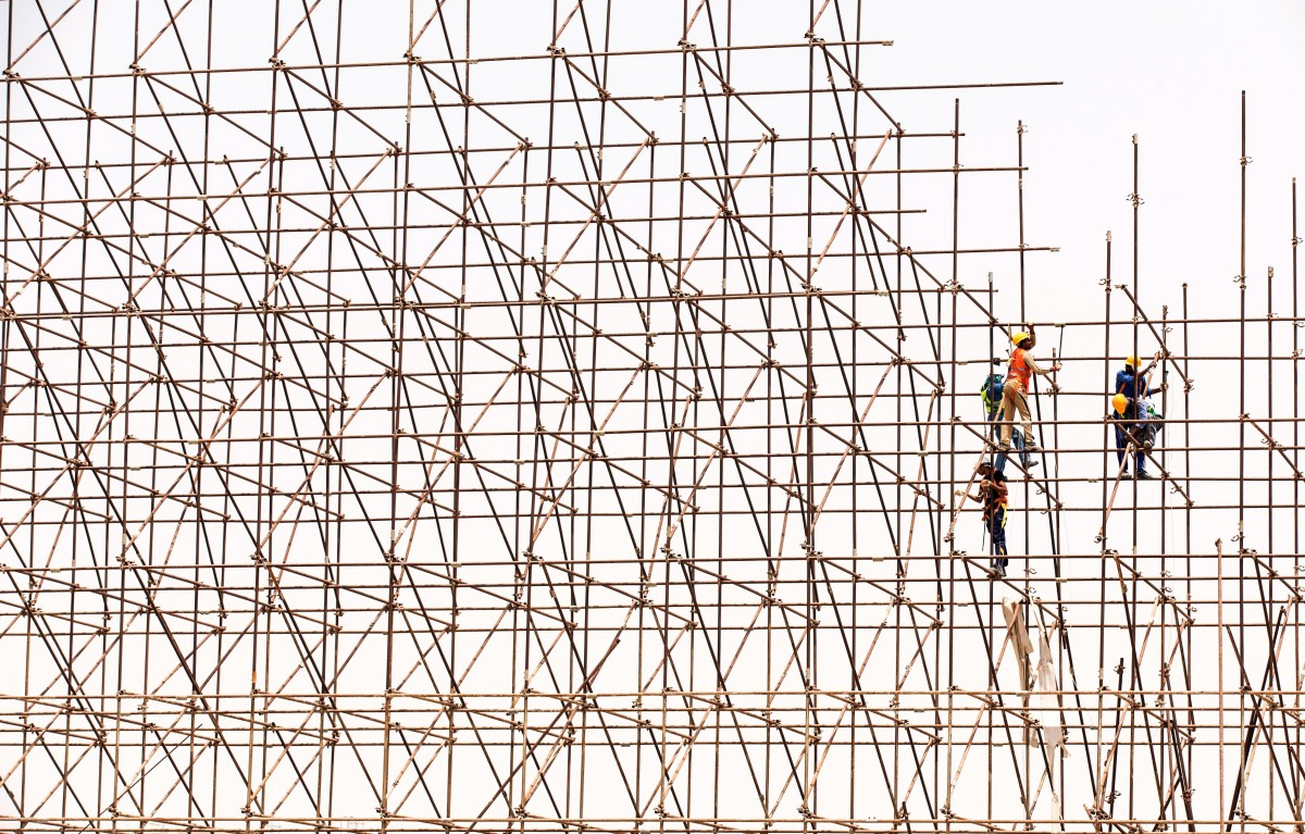 Three people on a large scaffold fixing something