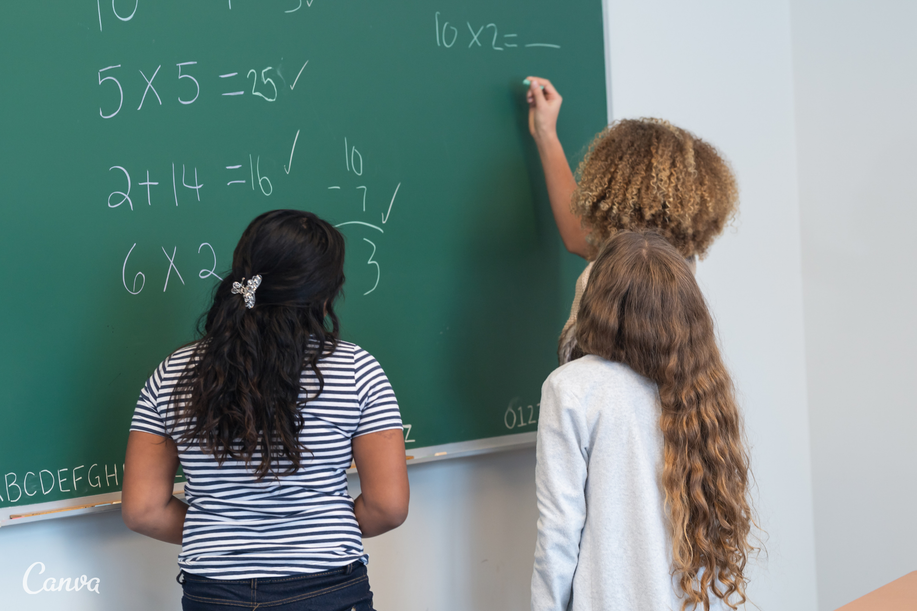 Two students solving math problems on a green chalk board, image from Canva