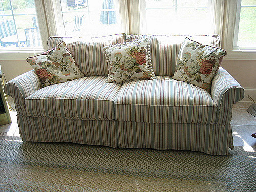 A skirted sofa with two pleats, rolled arms, and a straight cushion.