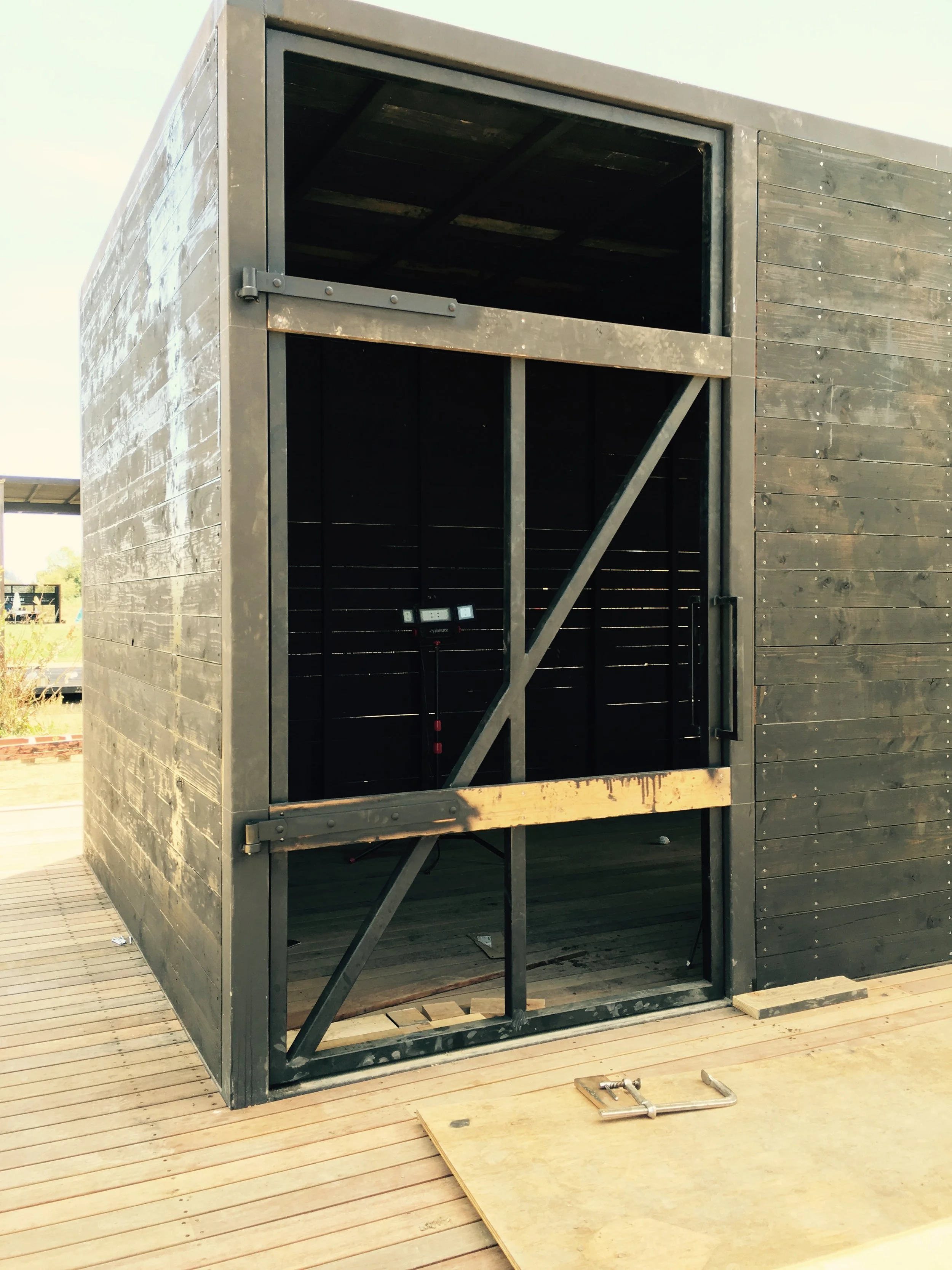 We are fabricating our own metal and wood doors for all the buildings. This one is a prototype for all the Ag Buildings. It will be on the chicken barns and other buildings. 5' wide x 10' tall. 150 lbs. Finished in Douglas Fir and Black Pine Tar. The door in the photo isn't complete. 