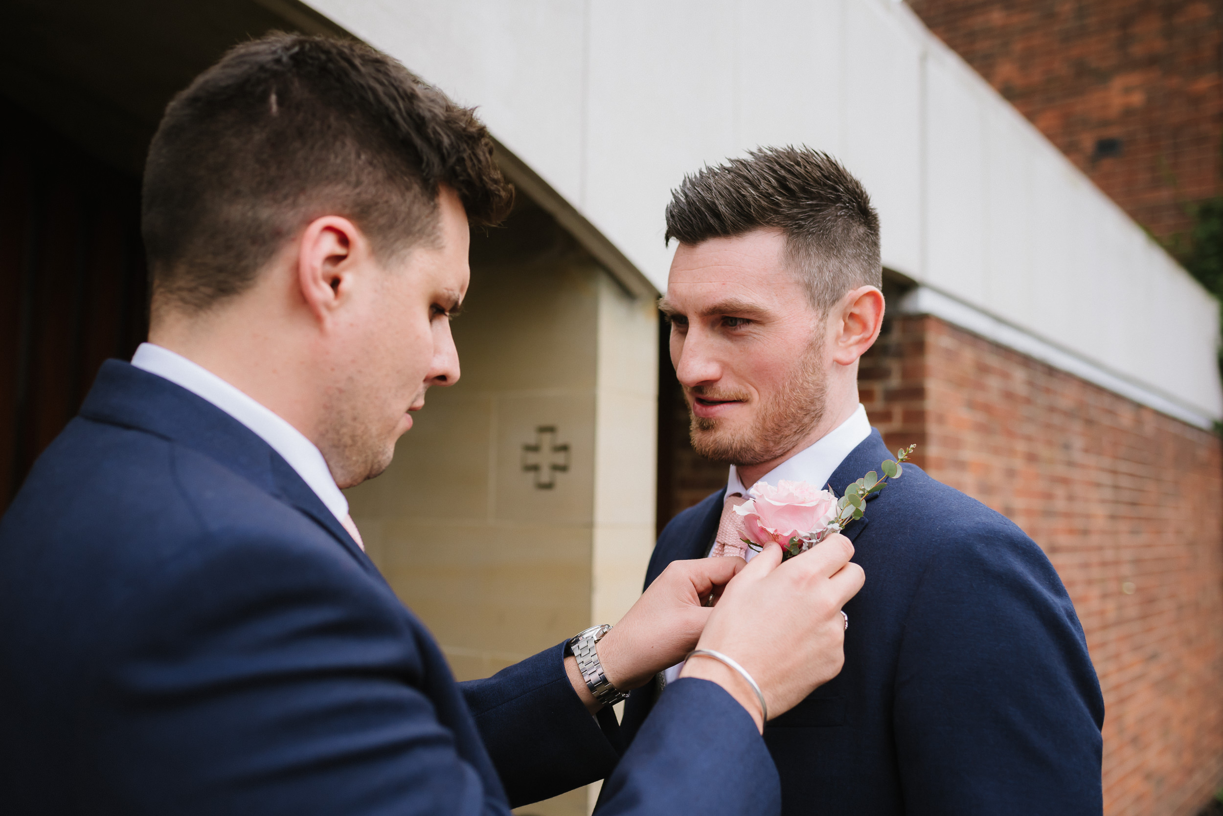 bestman fixing the grooms buttonhole