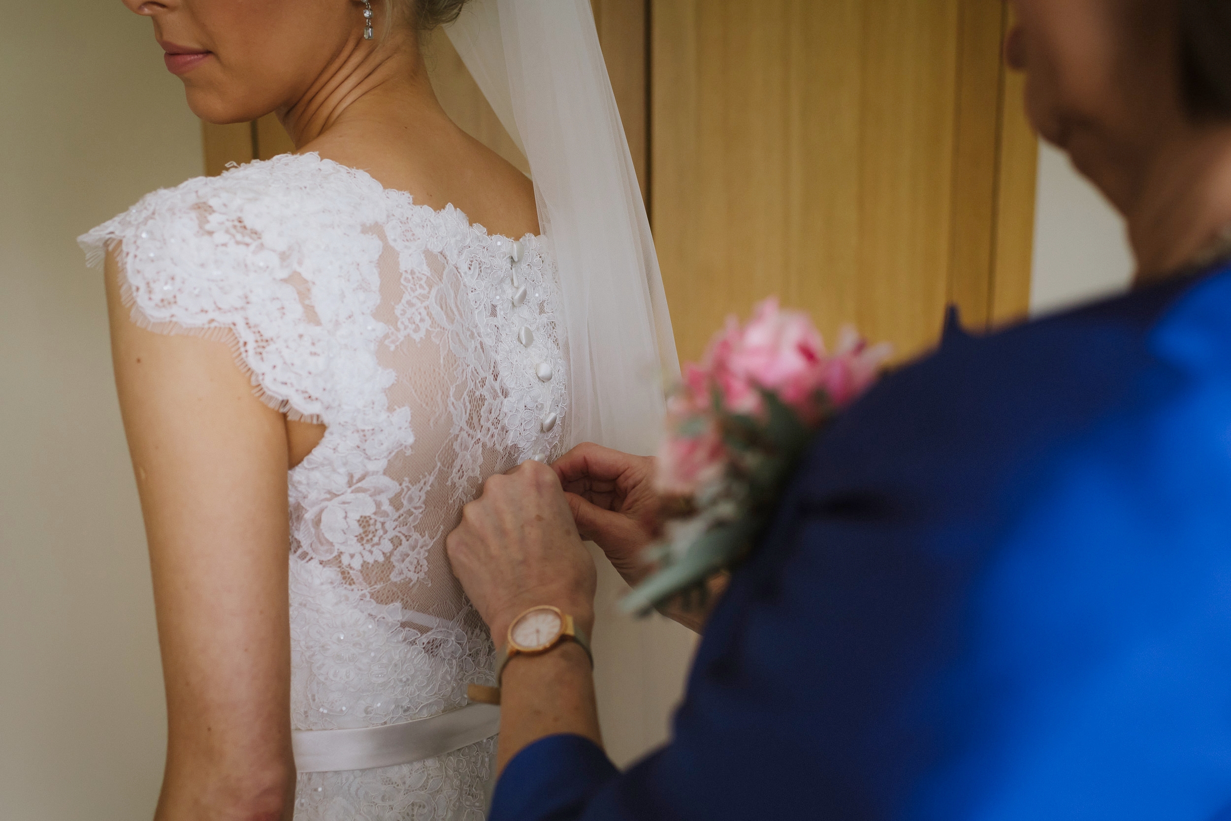 brides mother doing up the buttons on her dress