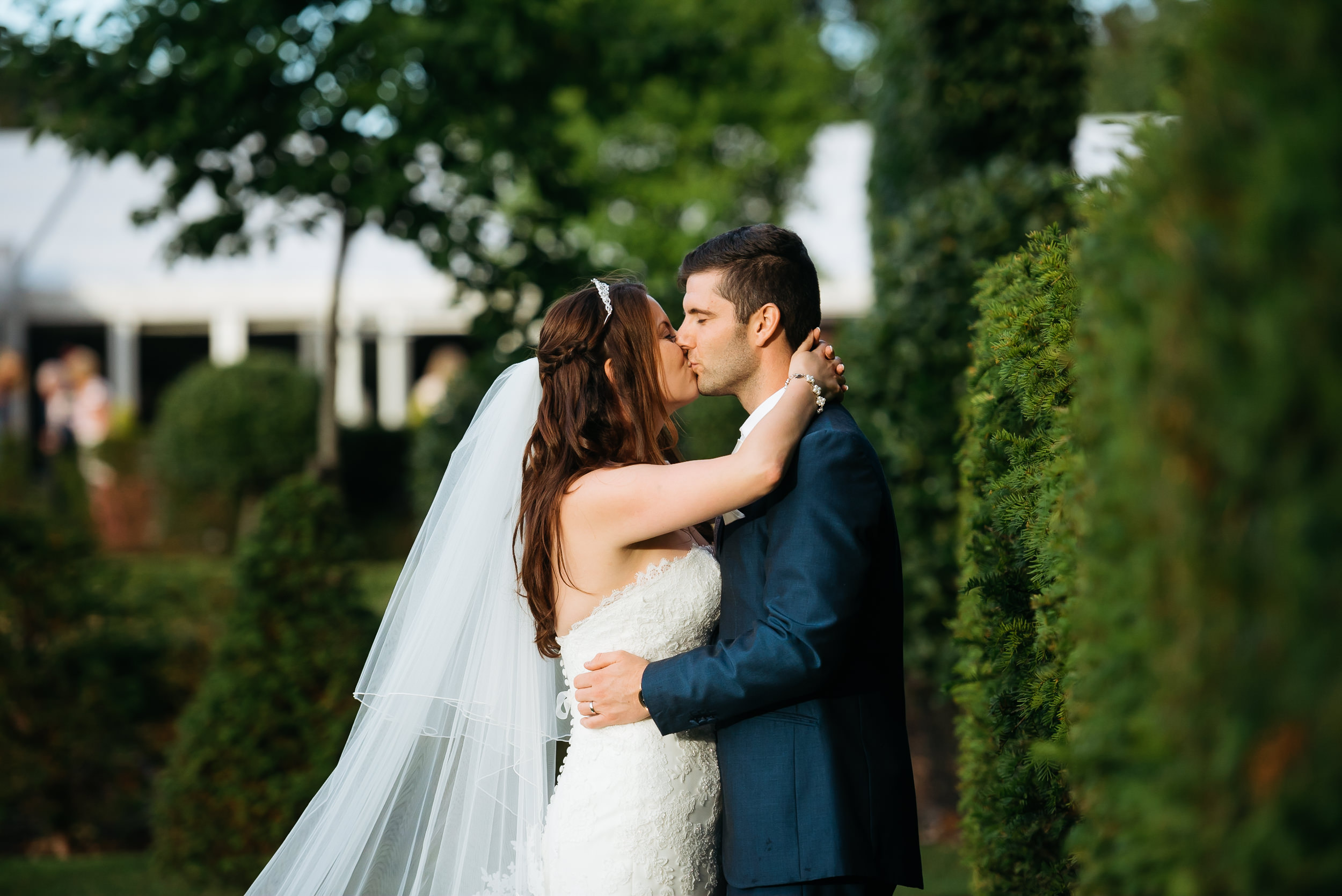 bride and groom kissing by a hedge at Hogarths hotel in Solihull