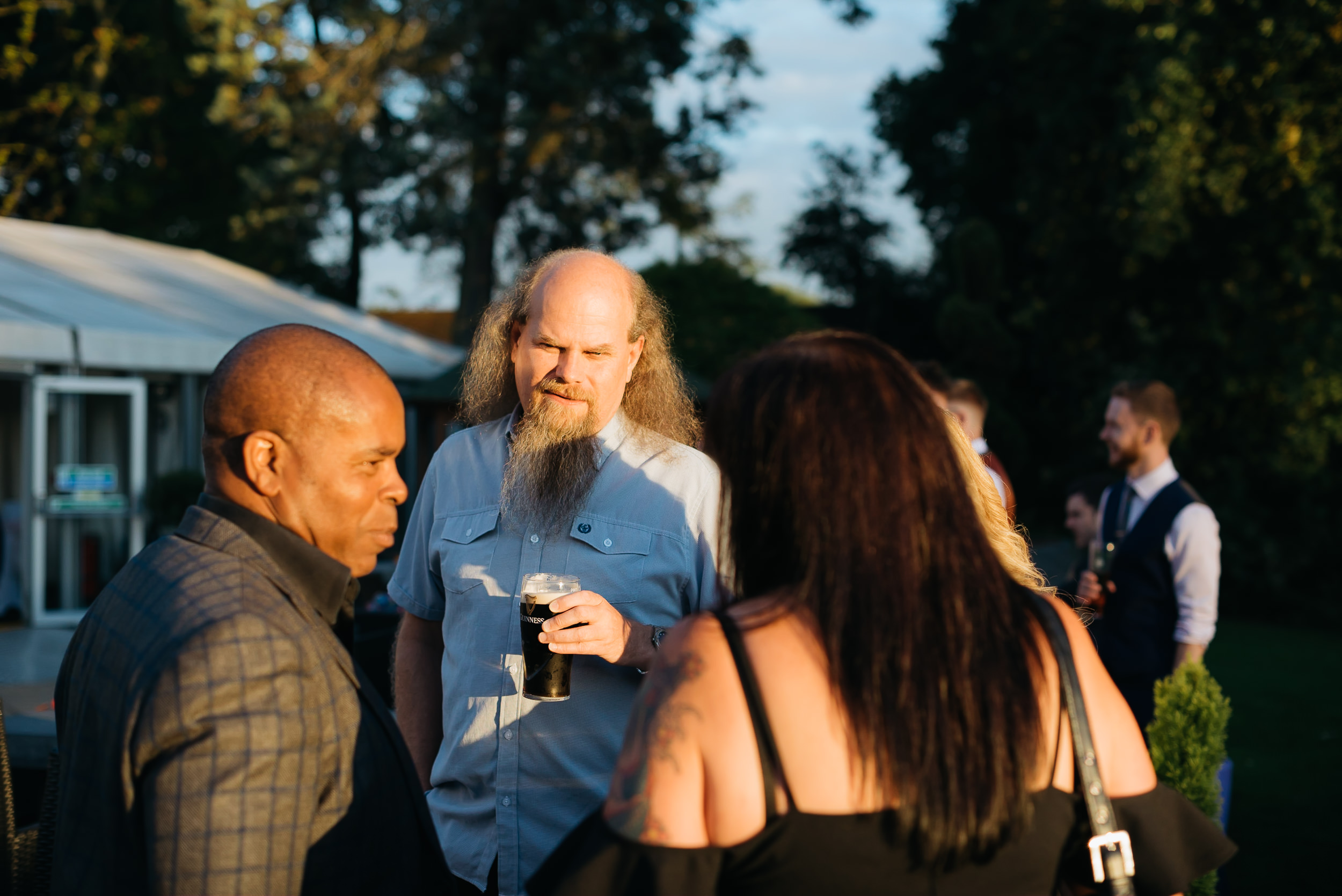 Wedding guests enjoying a drink in the evening sunshine