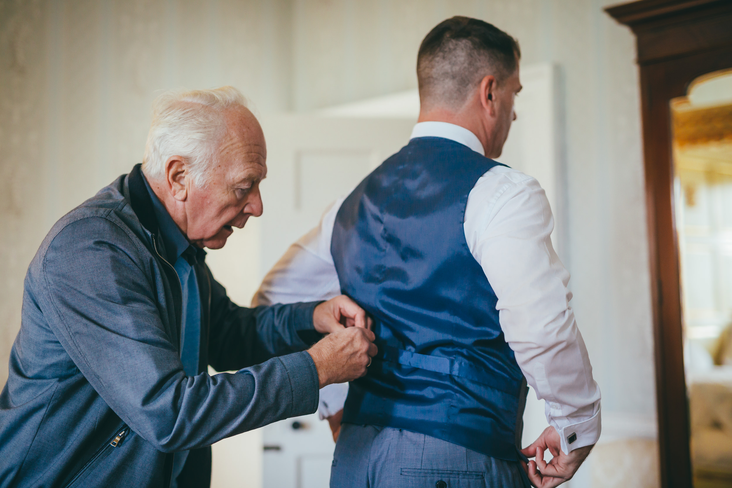 Groom having his waist coat tightened