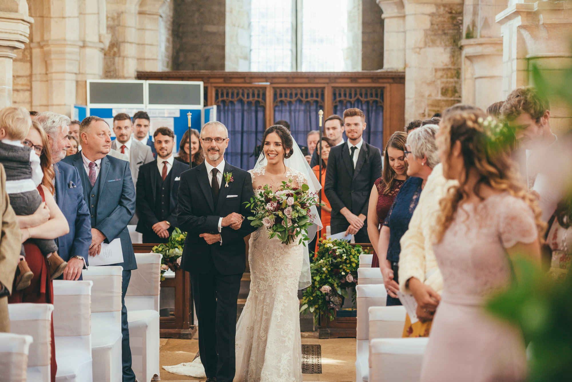 bride and her father walking down the aisle at harlaxton church