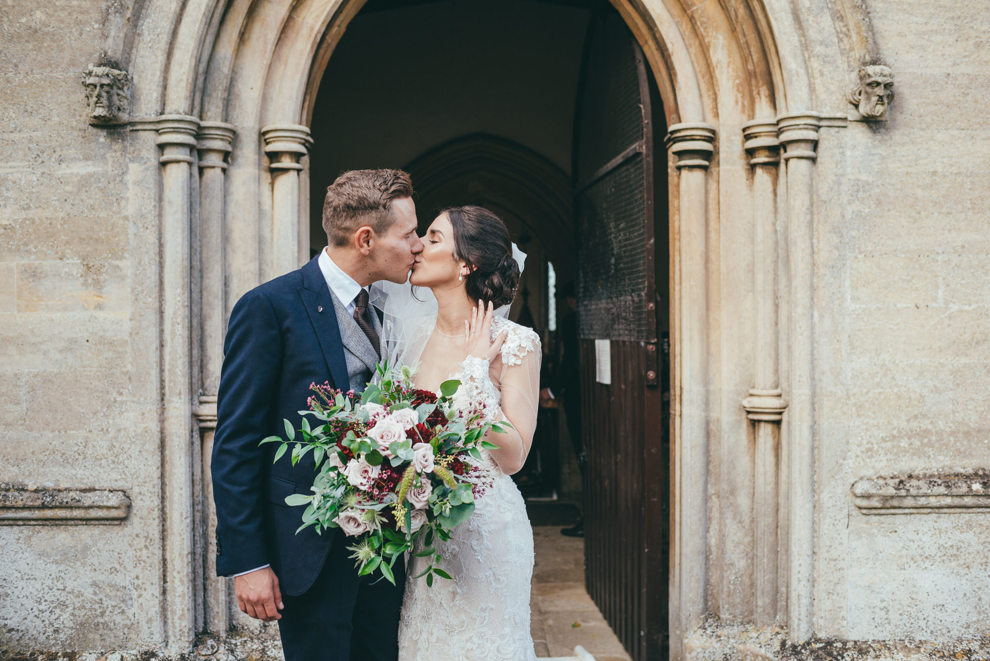 bride and grrom kiss outside of harlaxton church