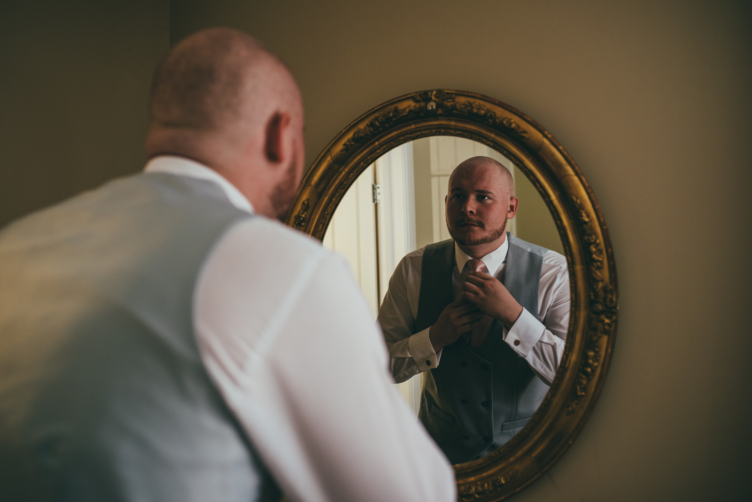 Groom fixing his tie in the mirror