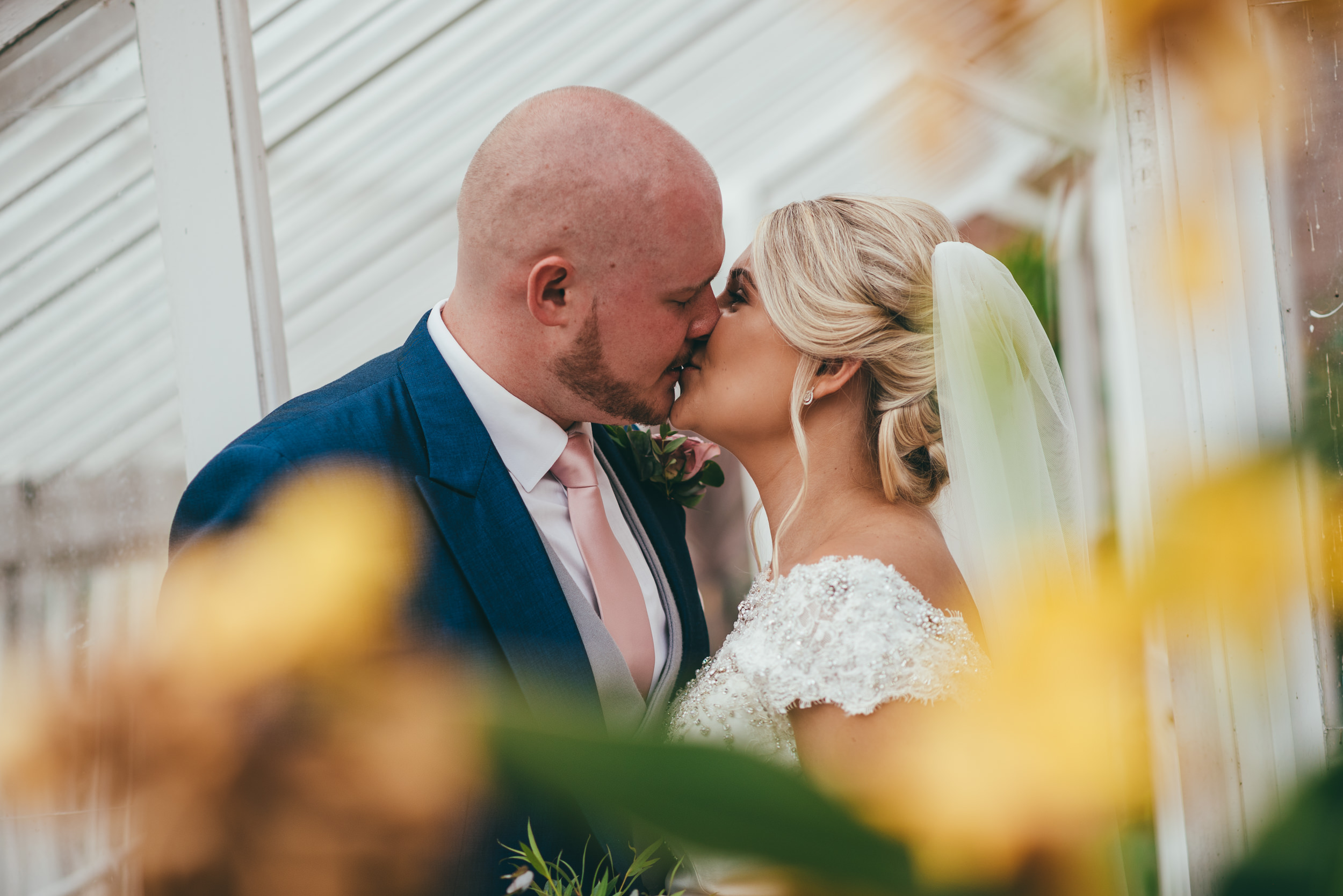 Bride and groom kissing in a greenhouse