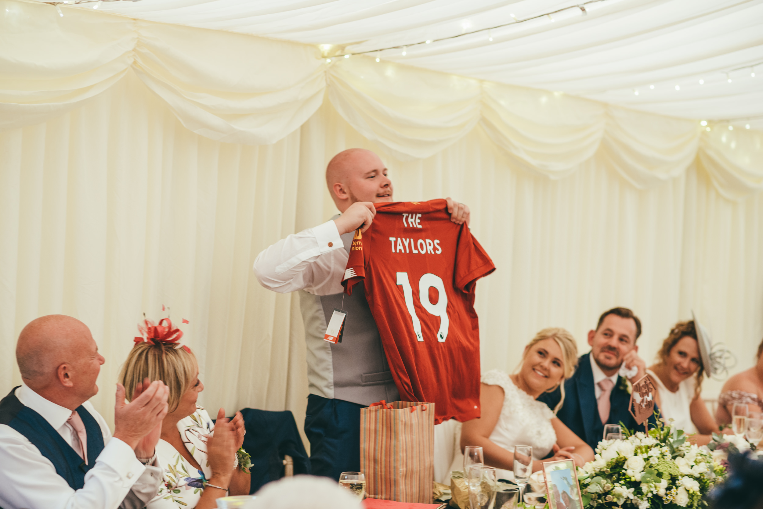 groom holding up a football shirt during the wedding speeches