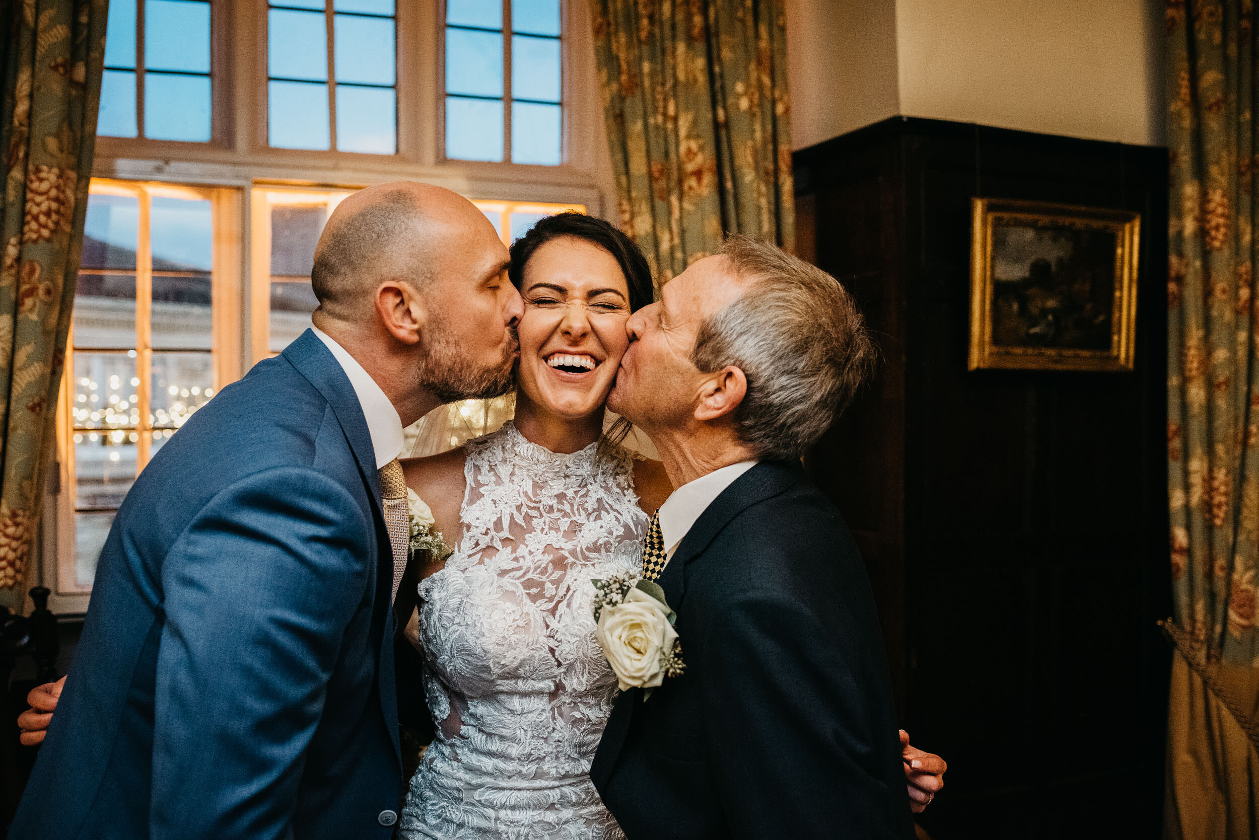 Bride being kissed by her father and her husband at the same time