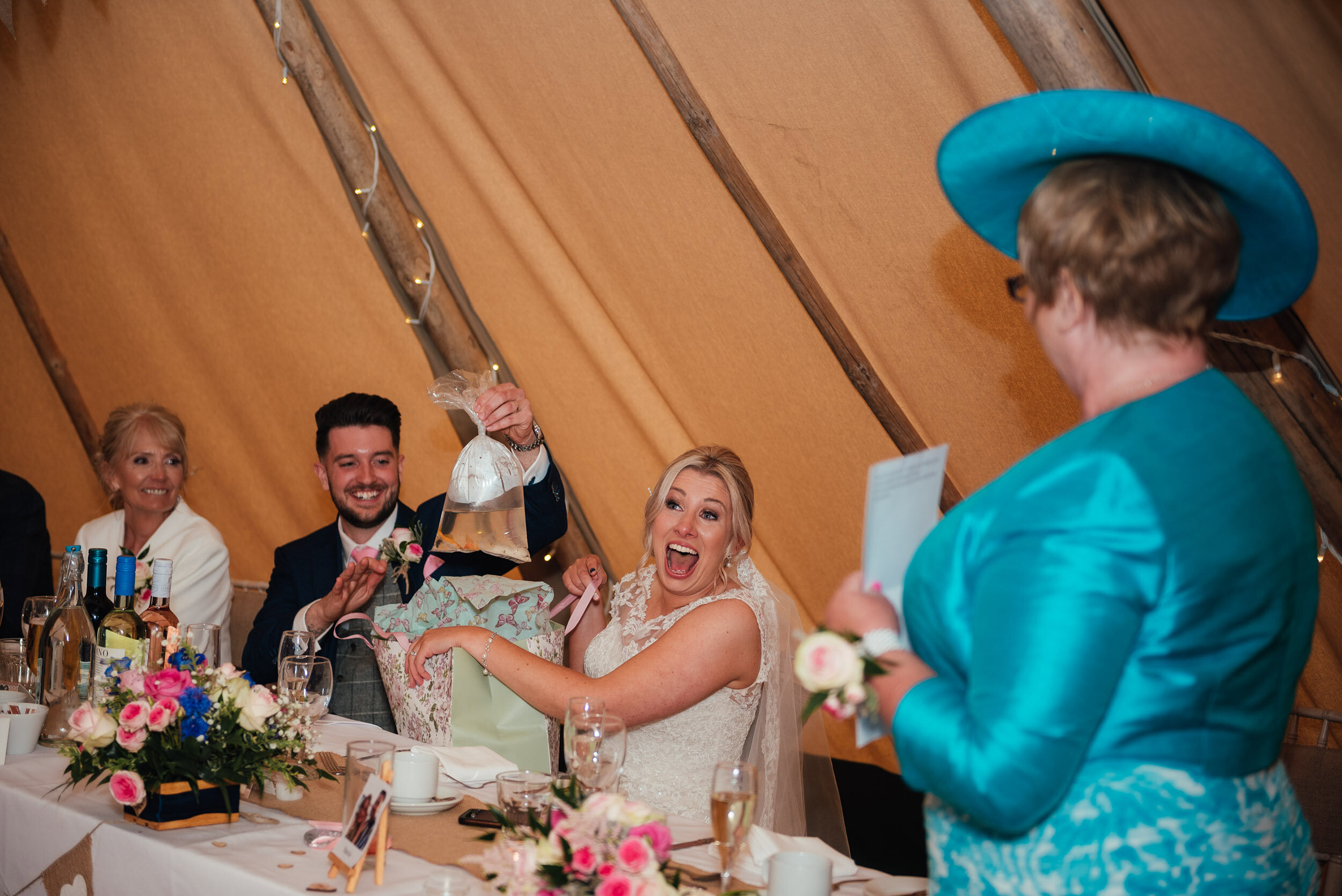 groom gives his bride a fish for a present during the wedding speeches