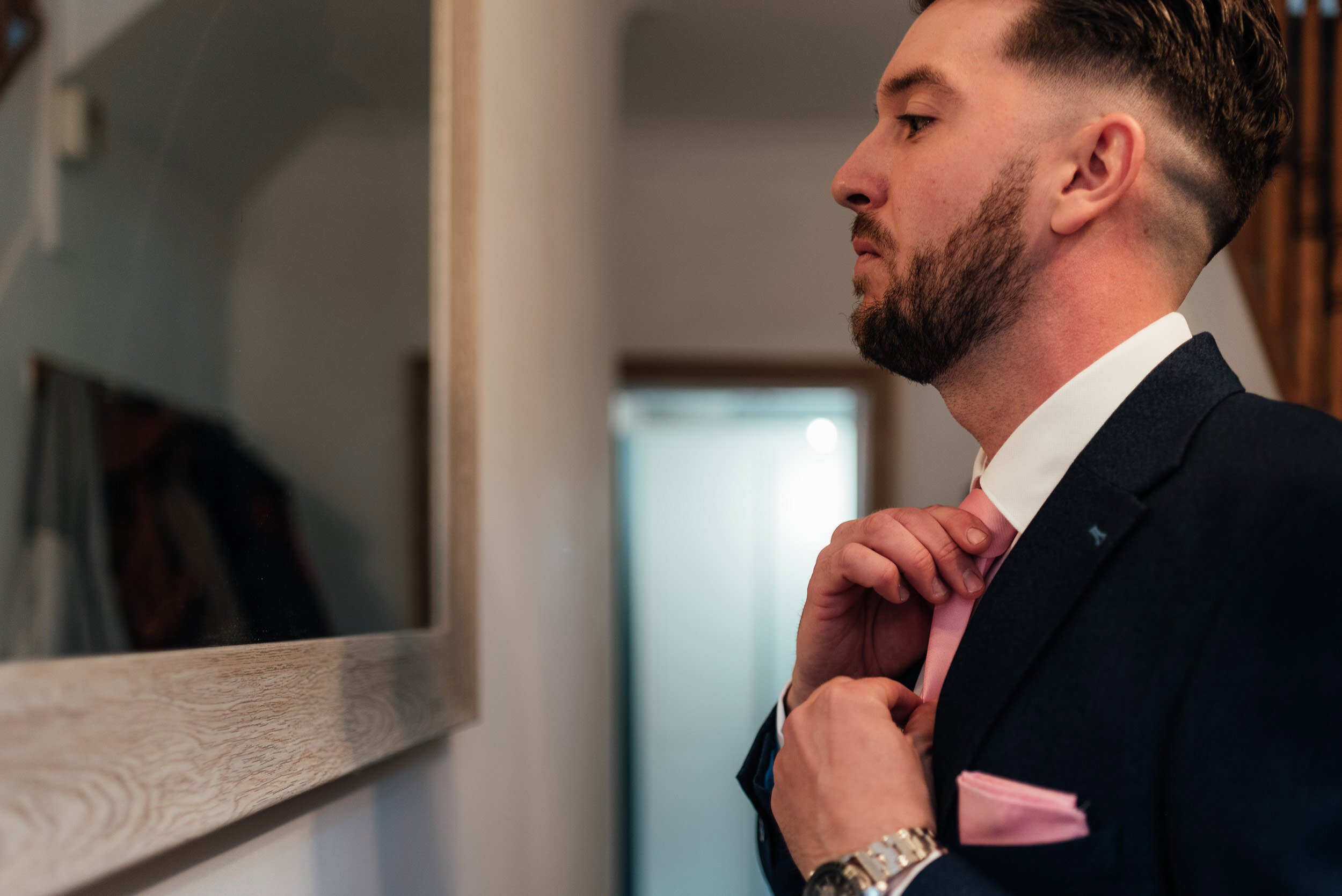 groom checking his tie in the mirror