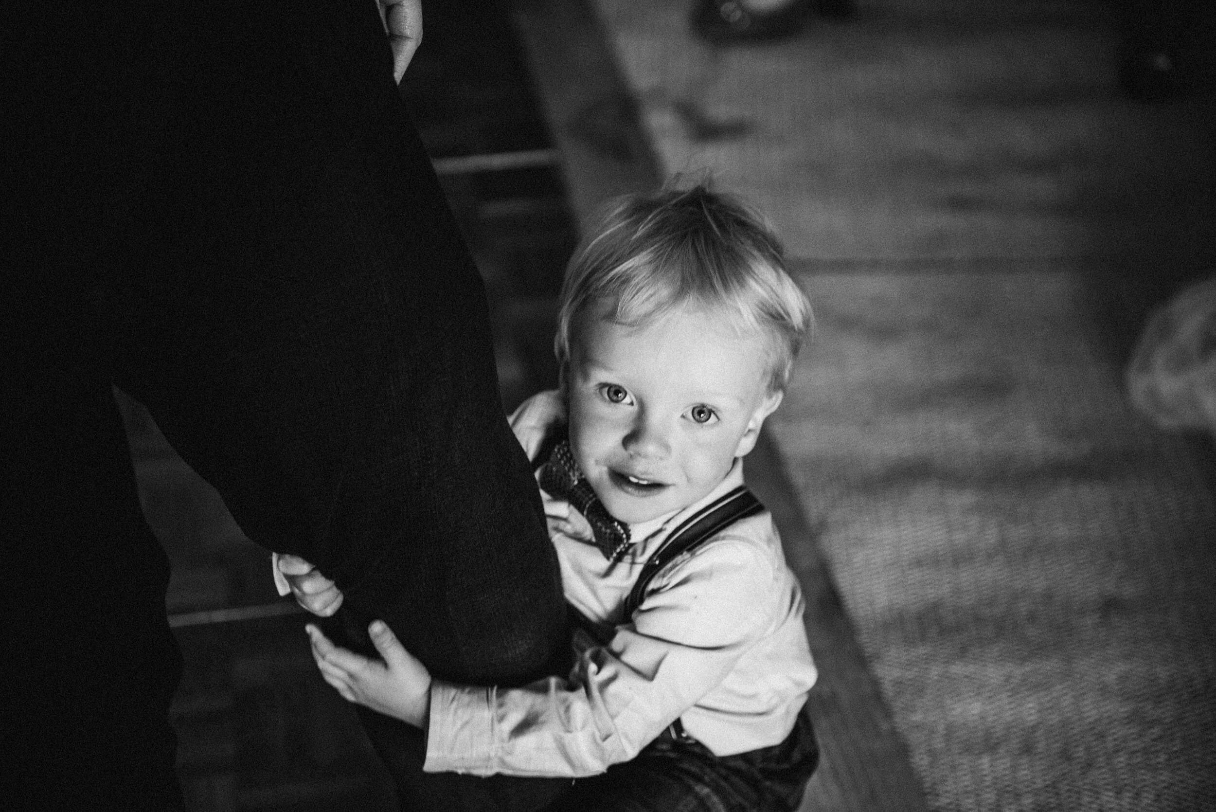 young wedding guest holding onto his dads leg