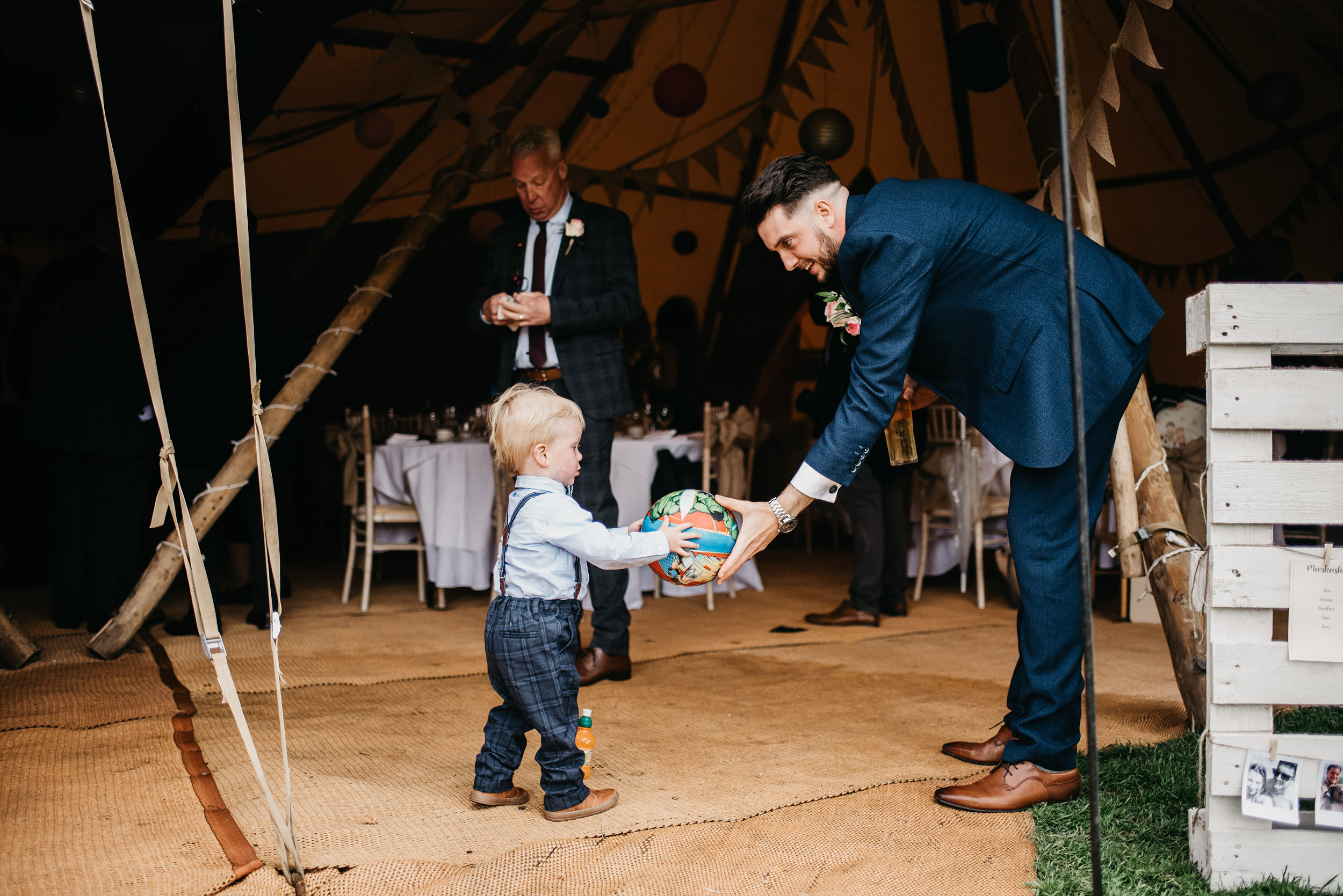 groom passes a football to a  young  boy