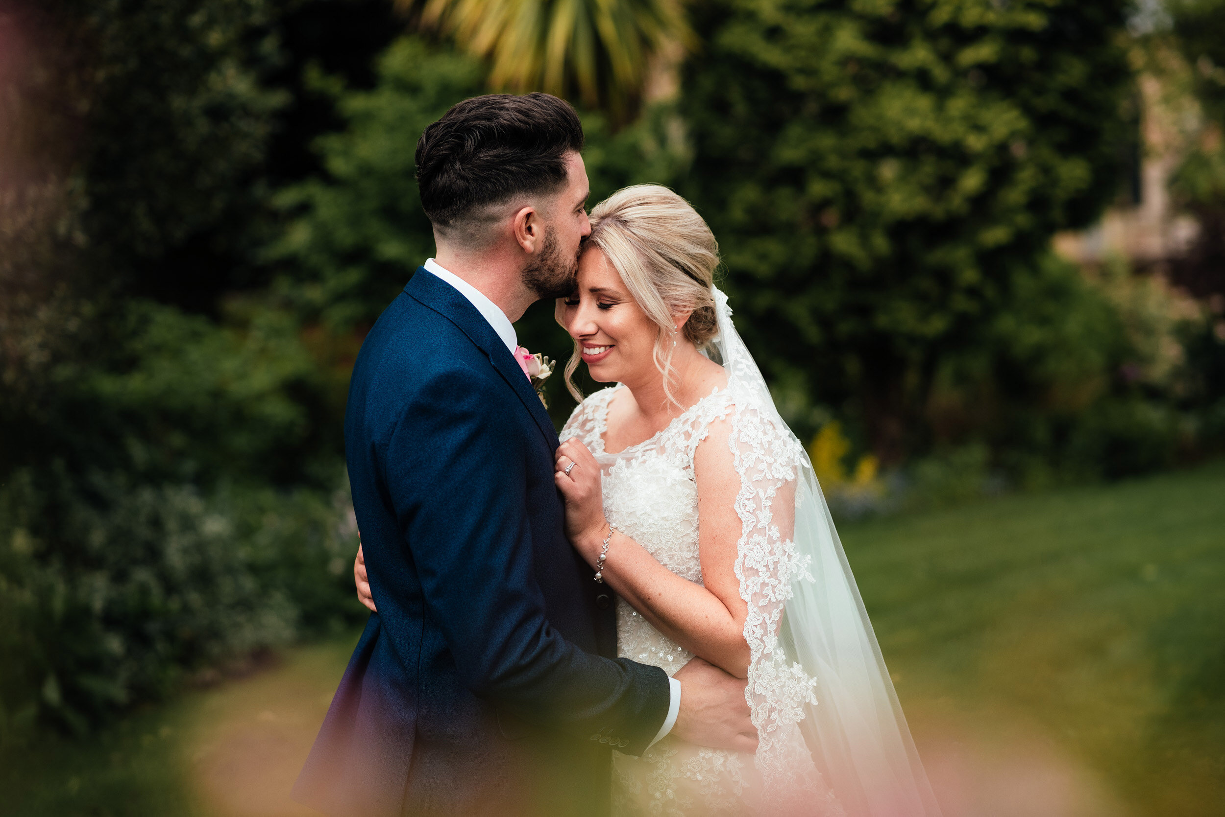 groom kisses his bride on the  forehead 