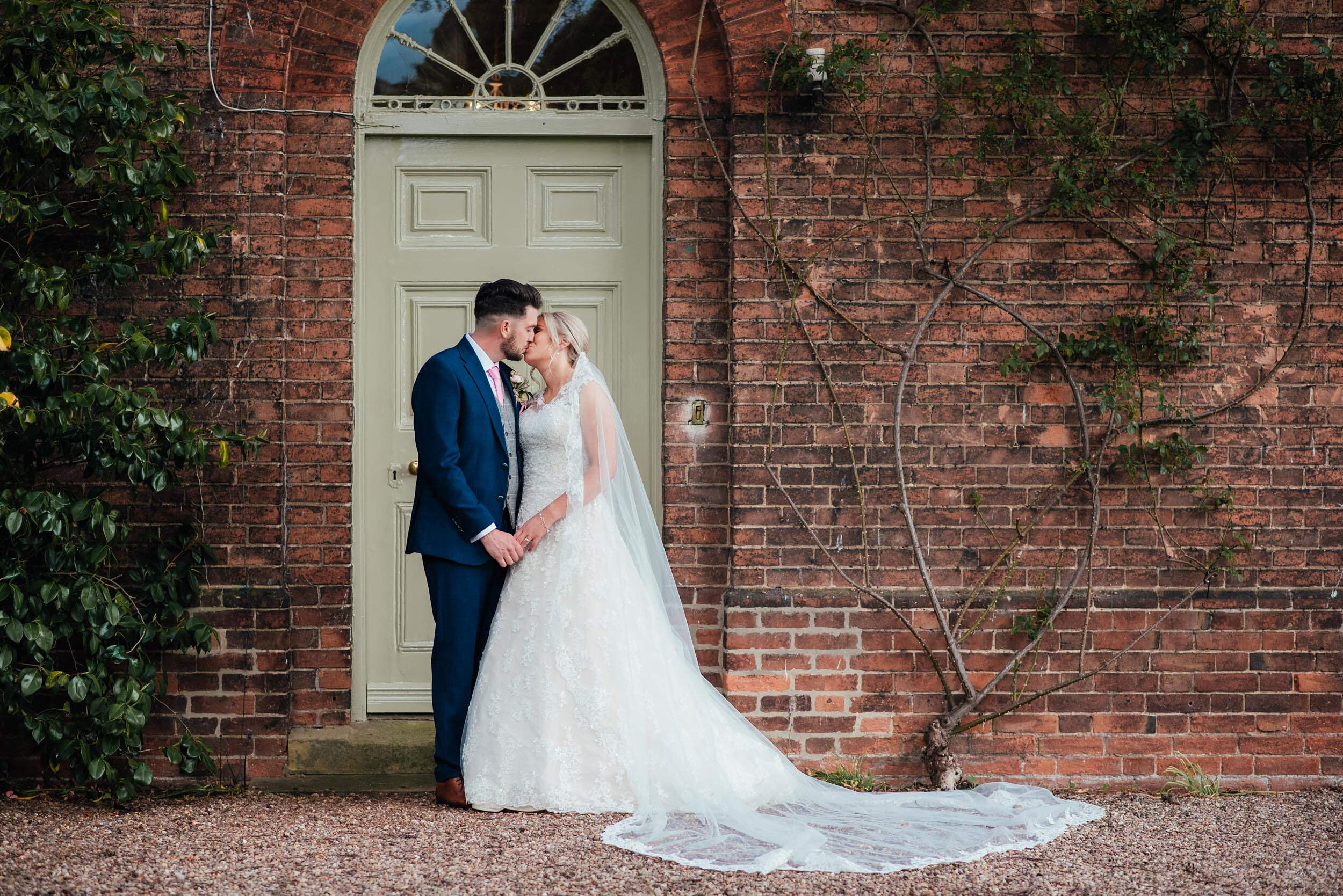 bride and groom kissing in front of a green door