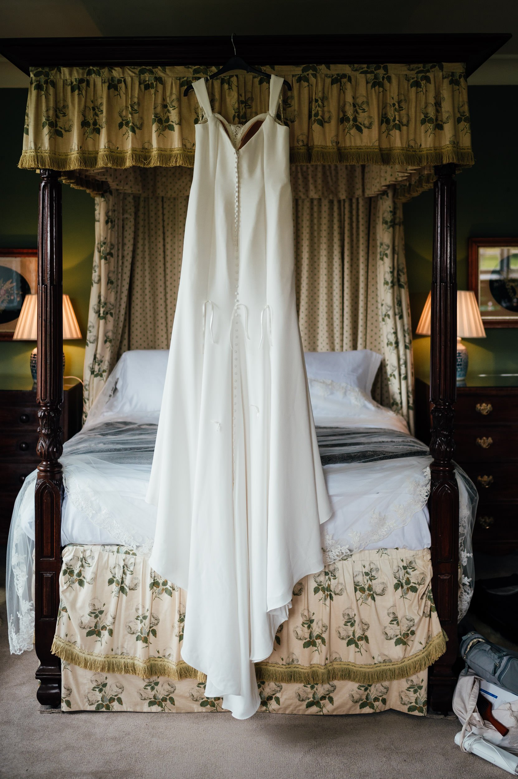 brides dress hanging from the four poster bed