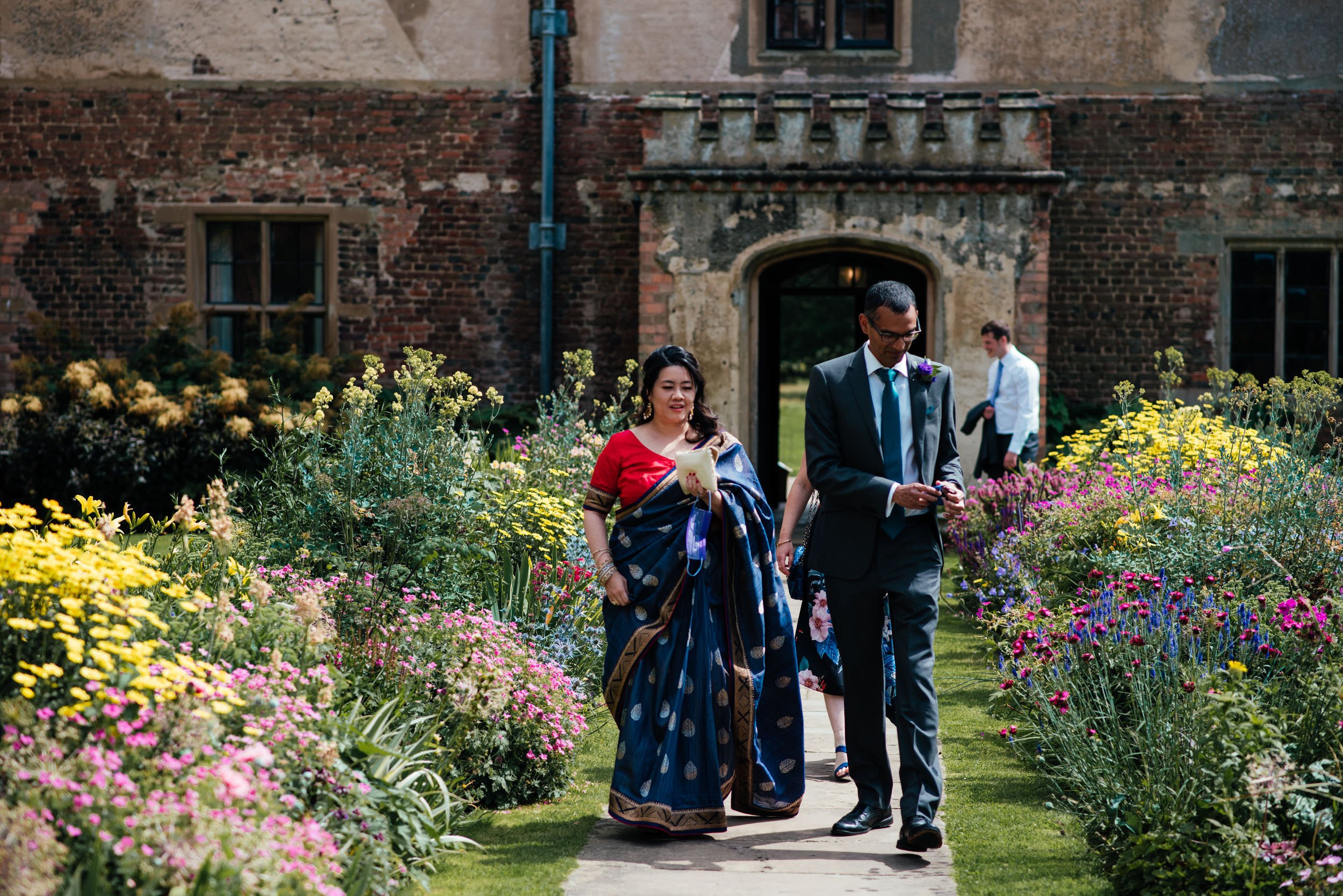 wedding guests walking through the flower garden at holme pierrepont hall