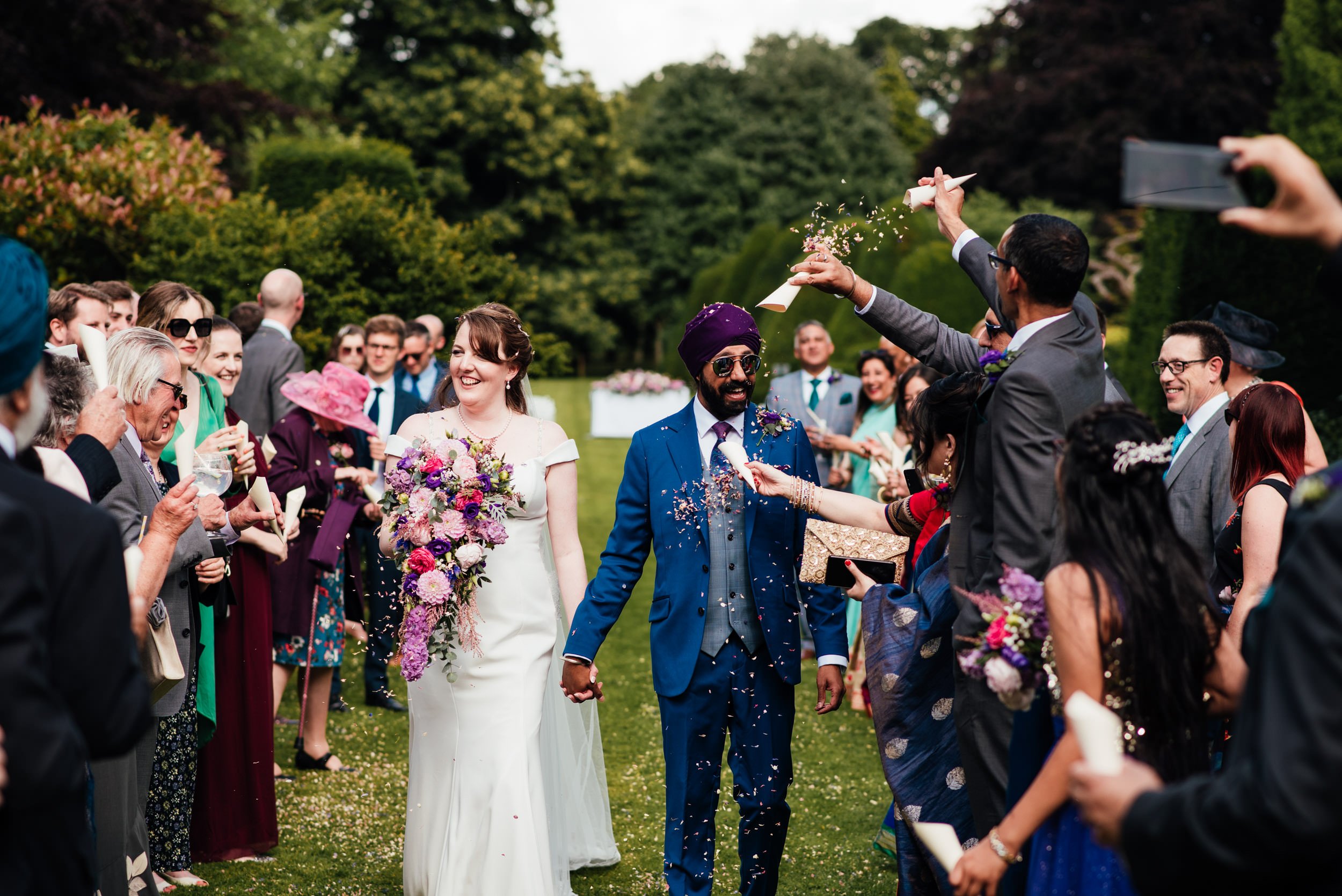 wedding guests throw confetti over the bride and groom at holme pierrepont hall