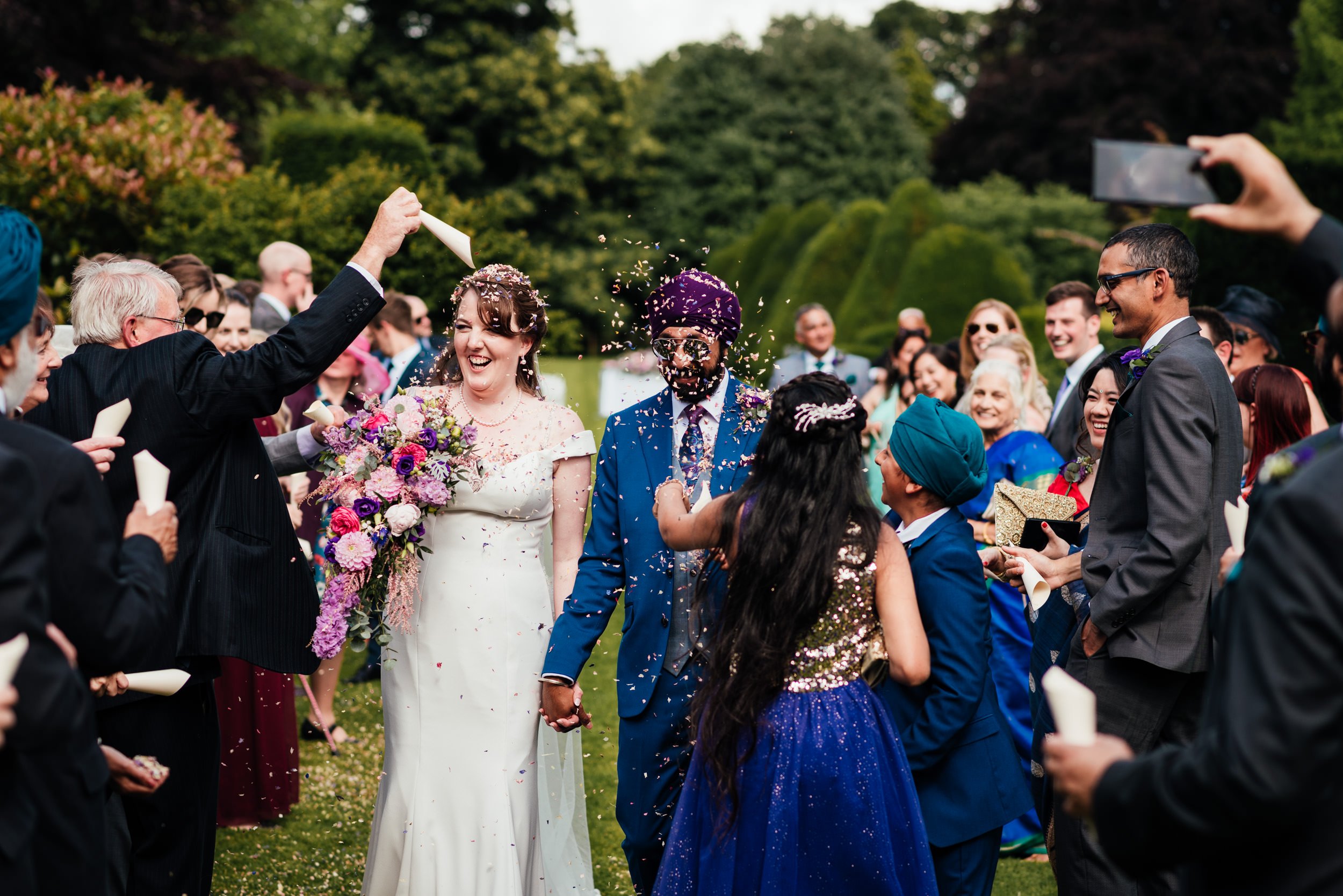 wedding guests throw confetti over the bride and groom at holme pierrepont hall