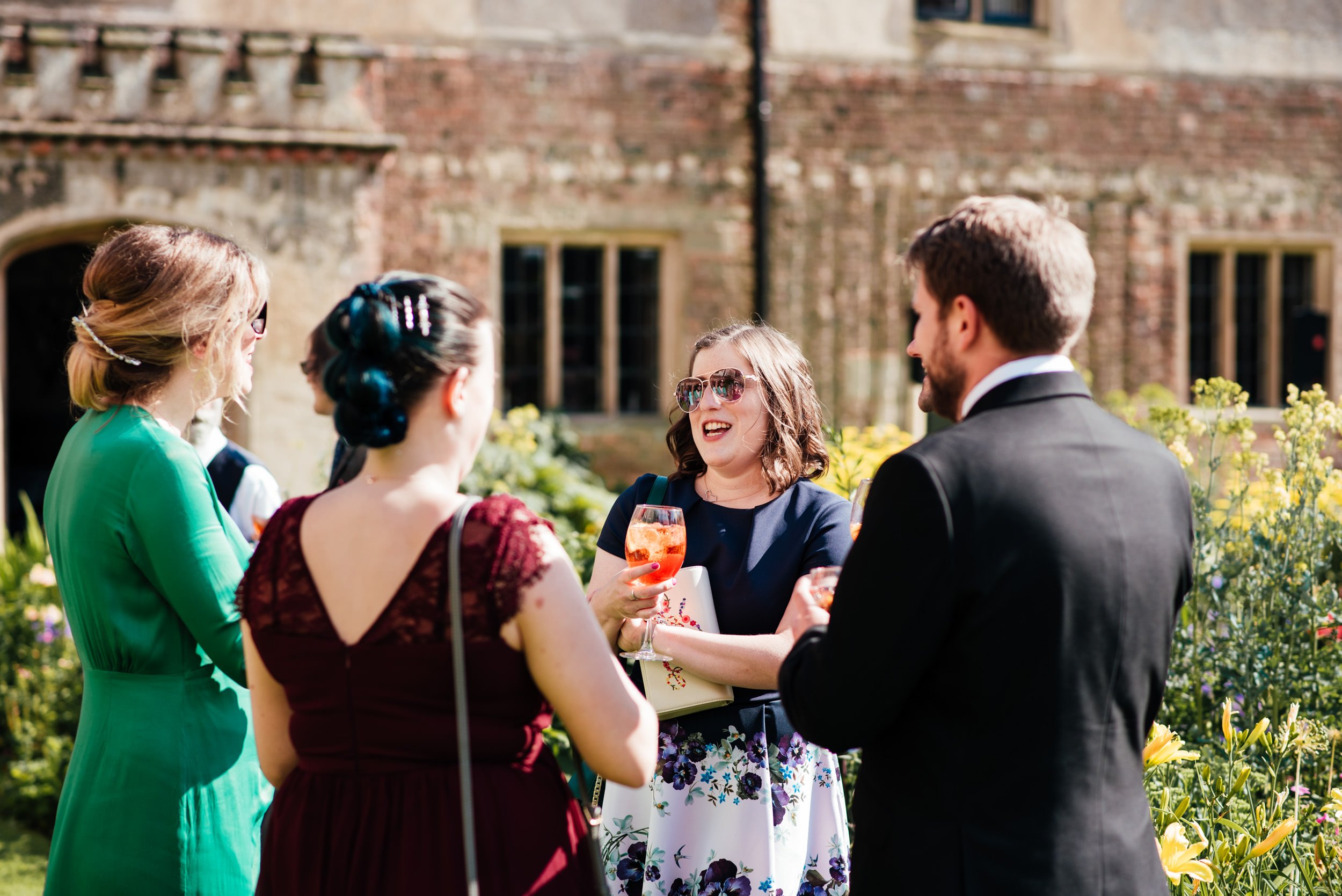 wedding guests having a drink in the flower garden at holme pierrepont hall