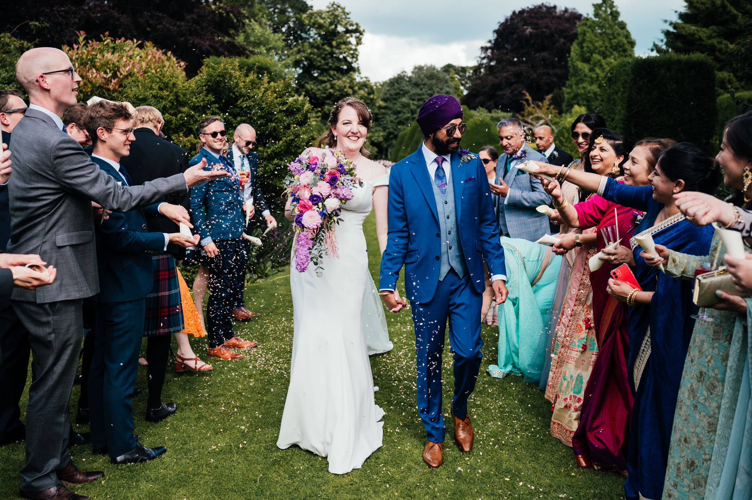 wedding guests throw confetti over the bride and groom at holme pierrepont hall