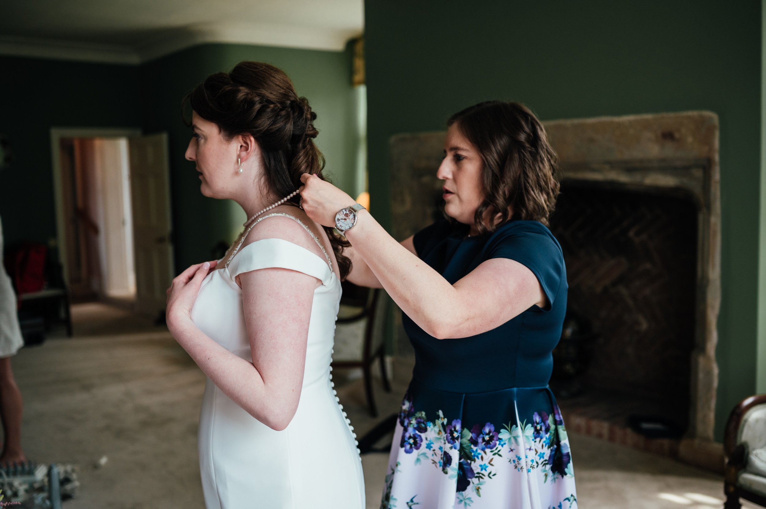 bridesmaid putting on the brides necklace