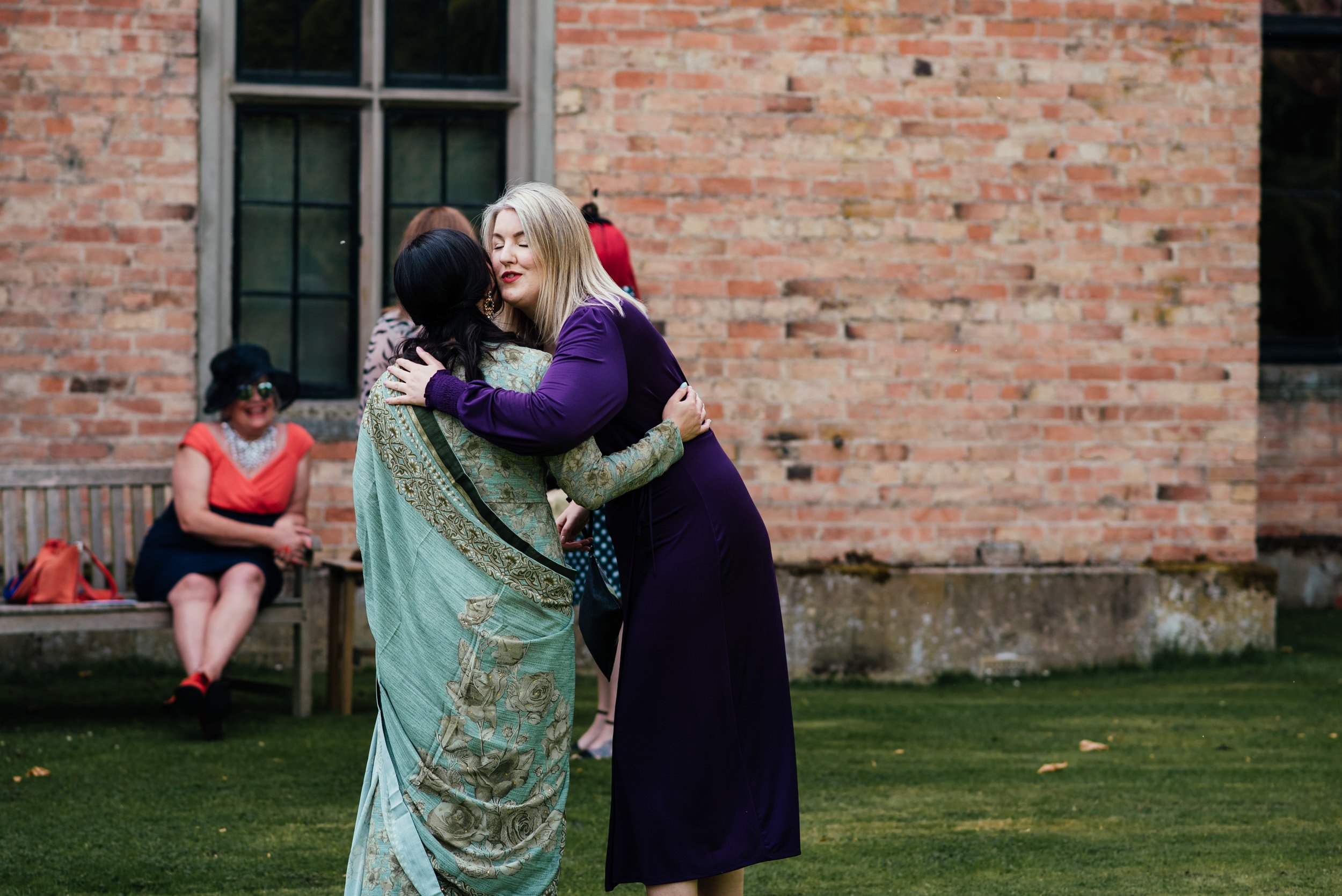 two wedding guests hugging