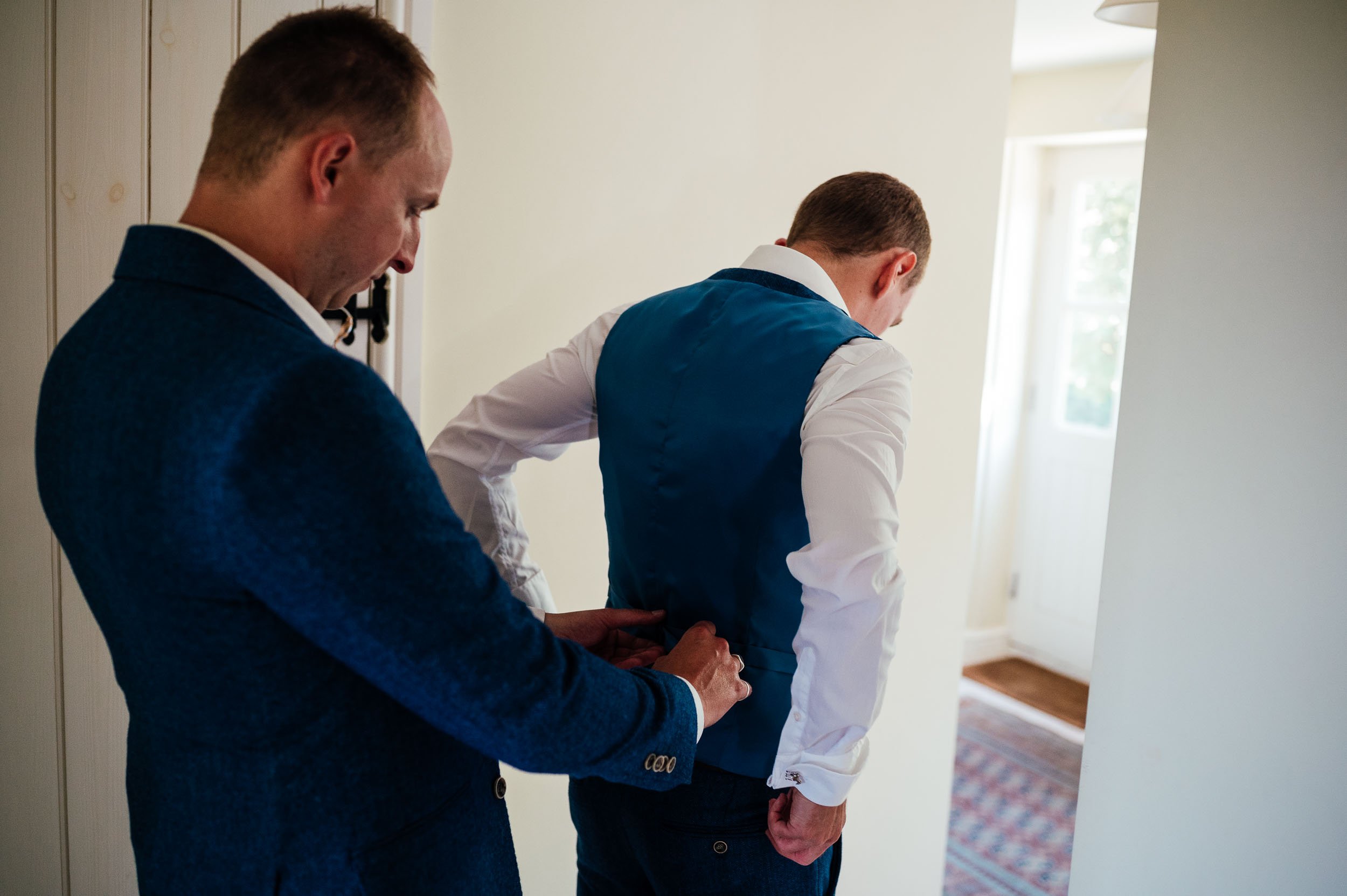 bestman fixing the grooms waistcoat